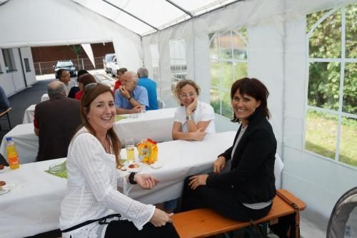 Eine Gruppe von Leuten sitzt an Tischen unter einem Zelt.