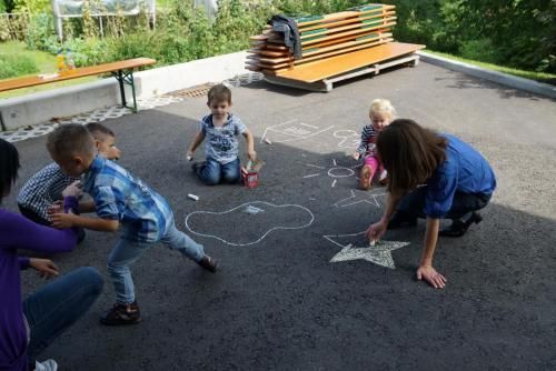 Eine Gruppe Kinder spielt mit Kreide auf dem Boden.