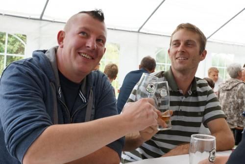 Zwei Männer sitzen an einem Tisch, trinken Bier und lächeln.