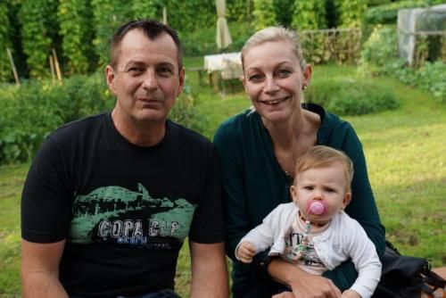 Ein Mann und eine Frau halten ein Baby mit einem Schnuller im Mund.