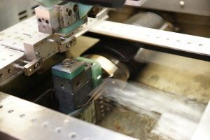 In einer Fabrik schneidet eine Maschine ein Stück Metall.