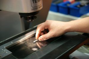 Eine Person betrachtet ein Stück Metall unter einem Mikroskop.