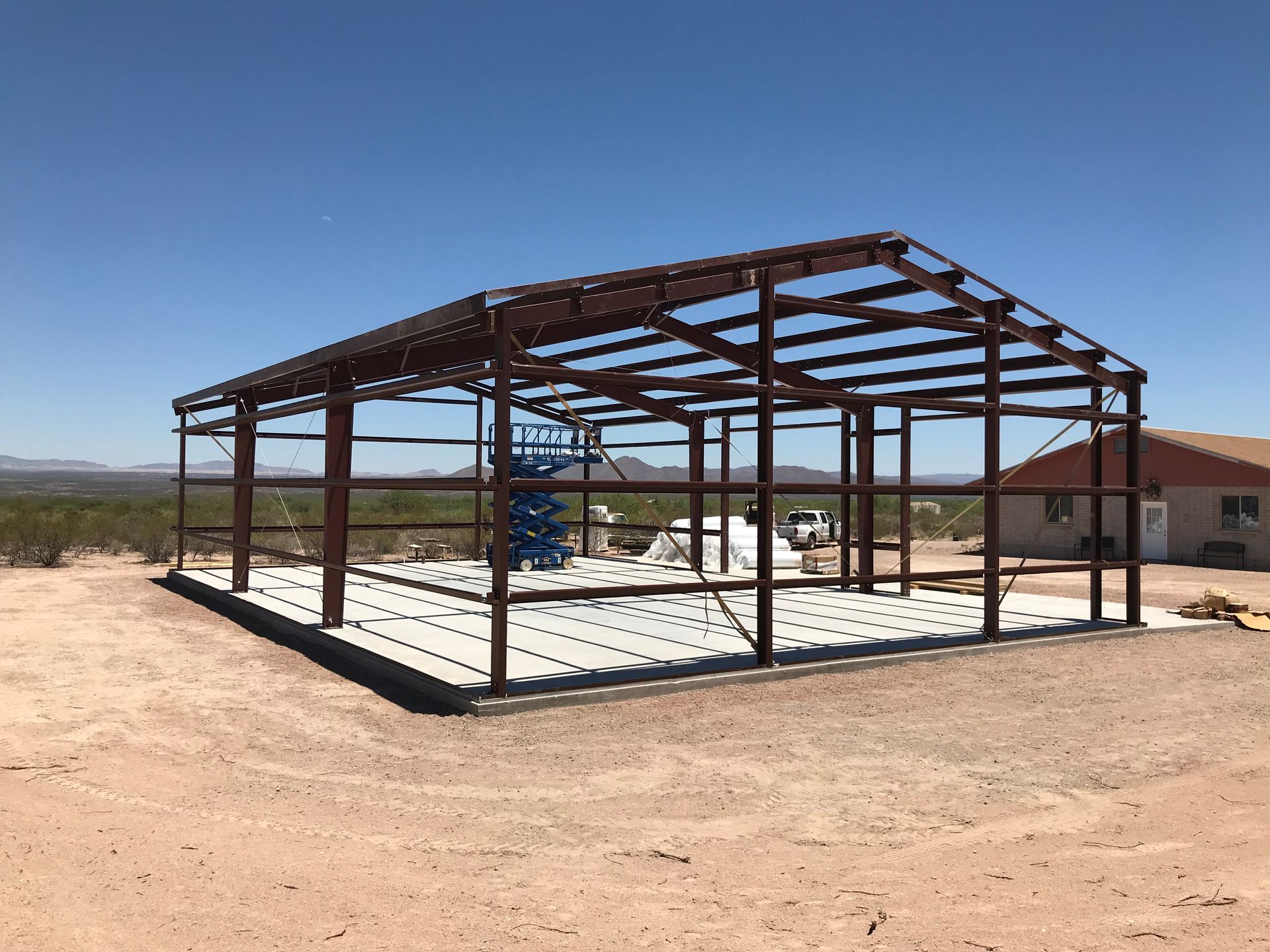 A large metal structure is being built in the middle of a dirt field.
