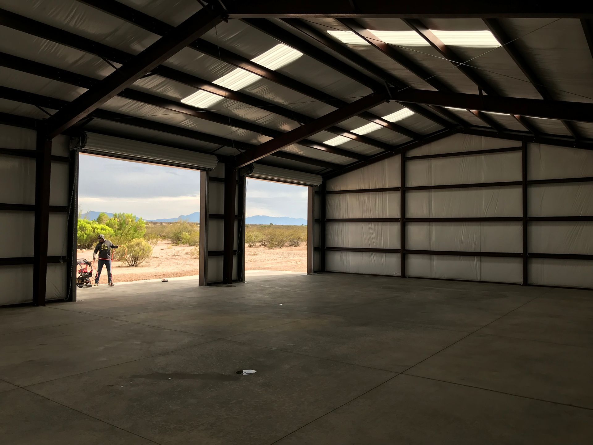 A man is standing in an empty building with the doors open.