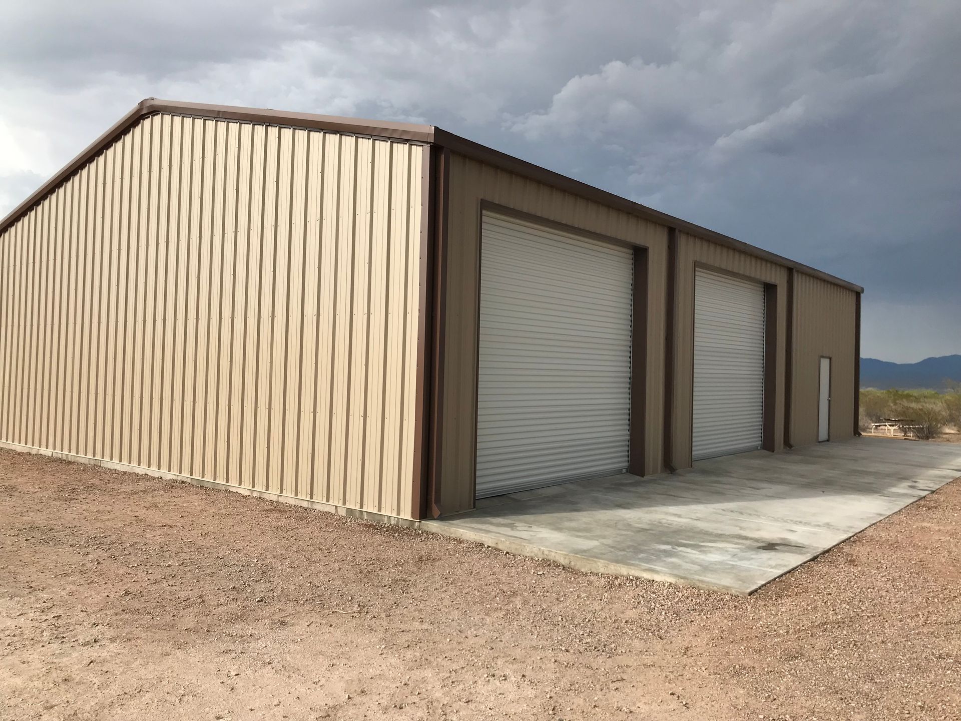 A large metal building with a concrete driveway in front of it.