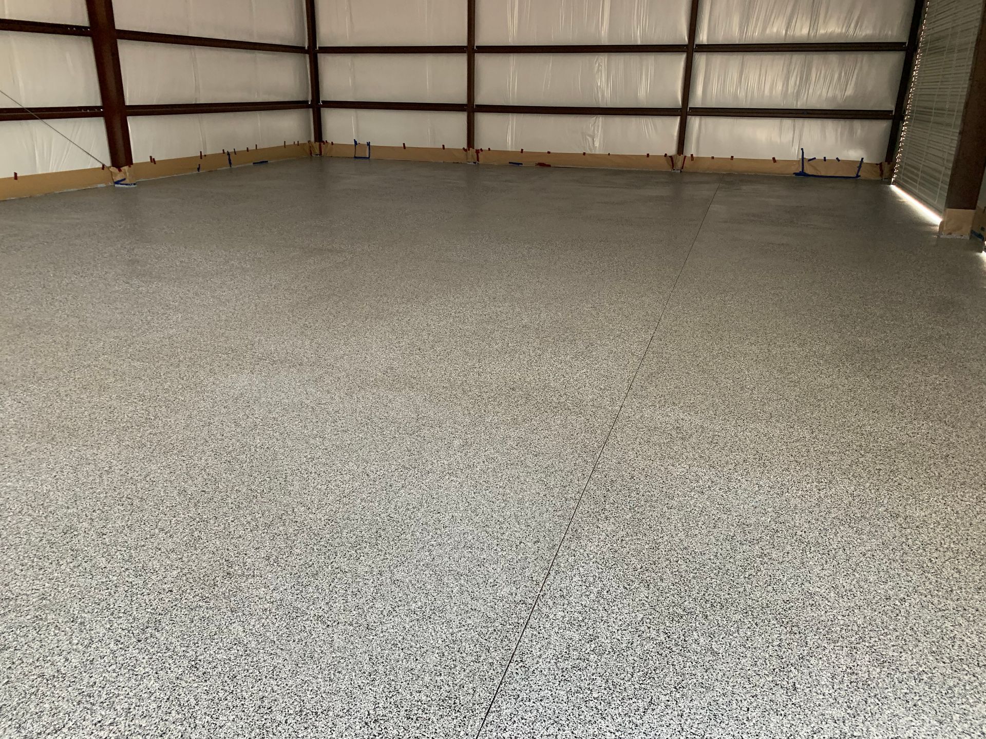 A garage with a gray floor and a white wall.