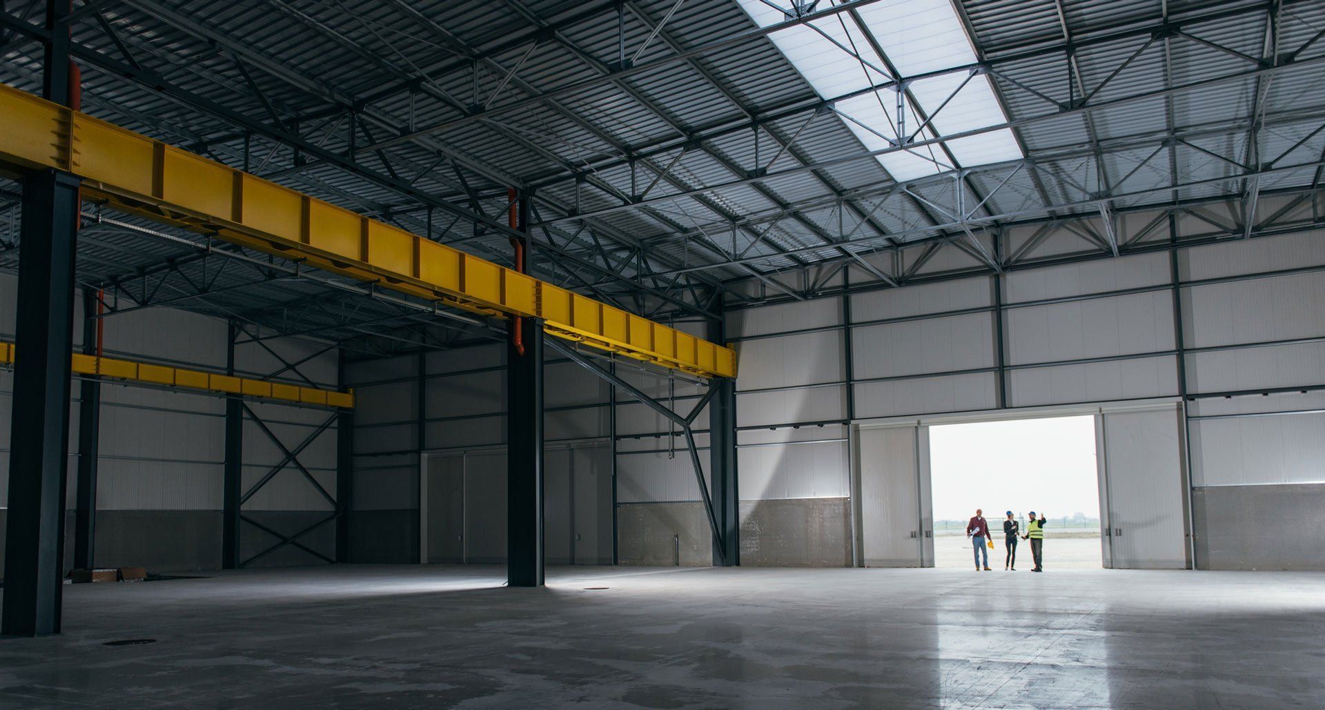 A group of people are standing inside of an empty warehouse.