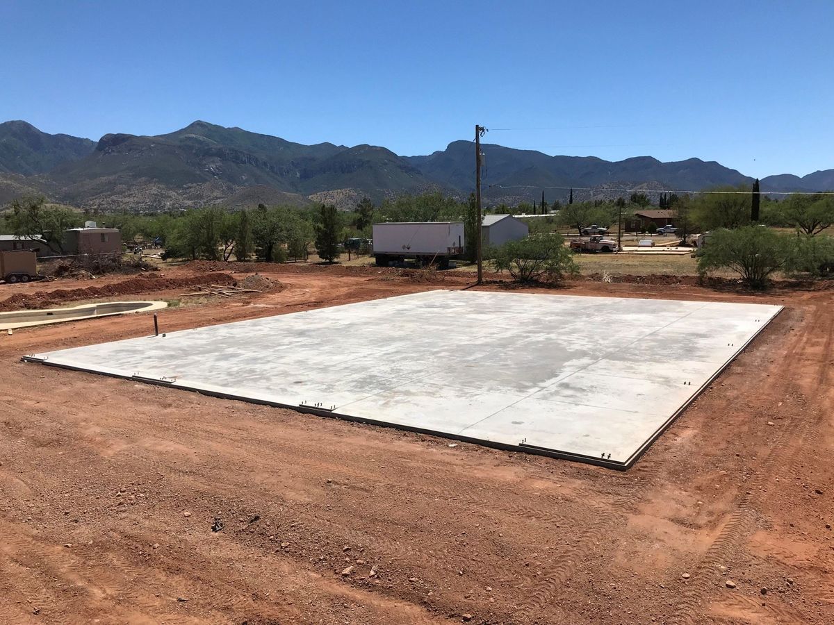 A large concrete slab is sitting in the middle of a dirt field.