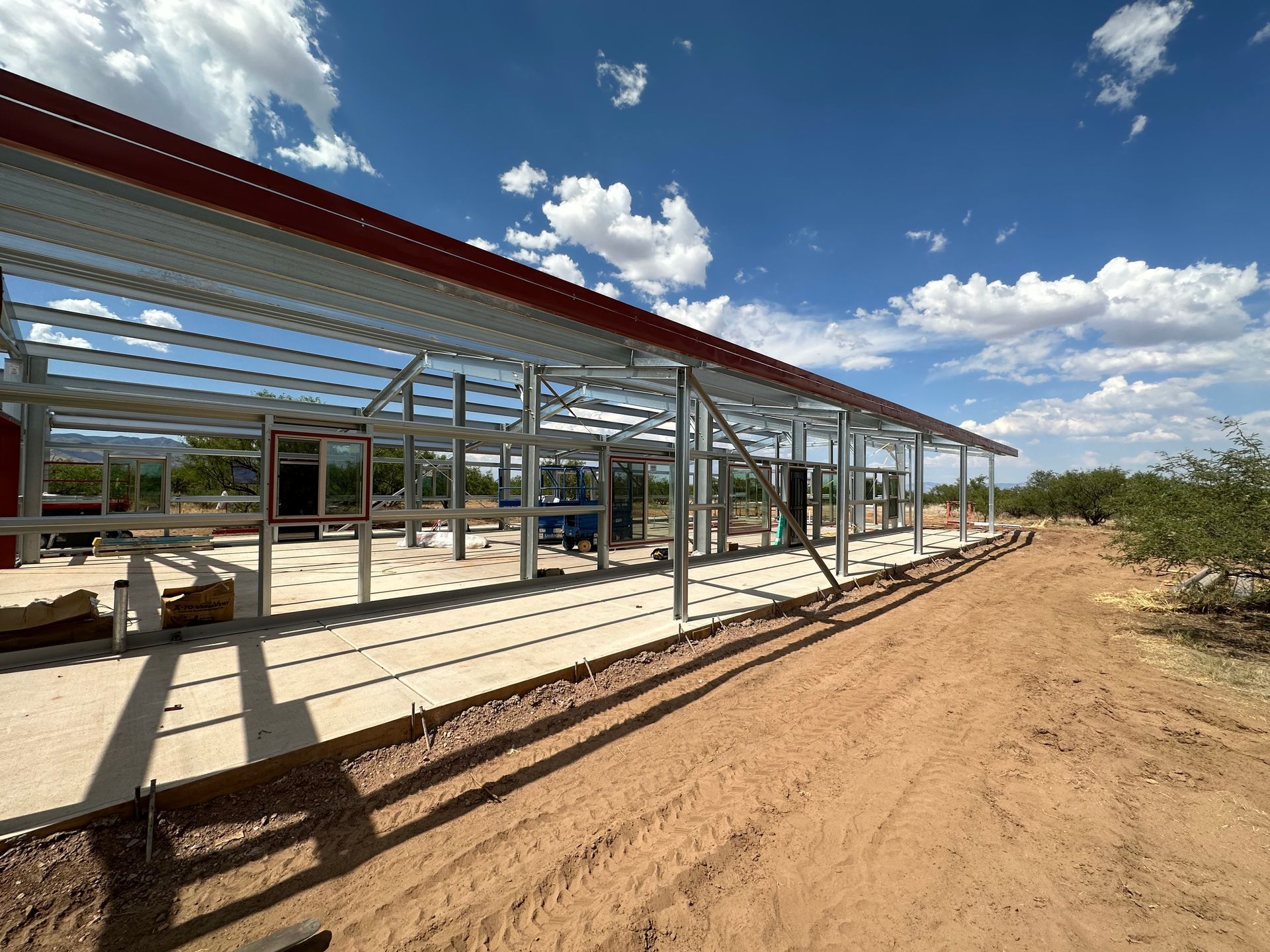 A large metal structure is being built in the middle of a dirt road.
