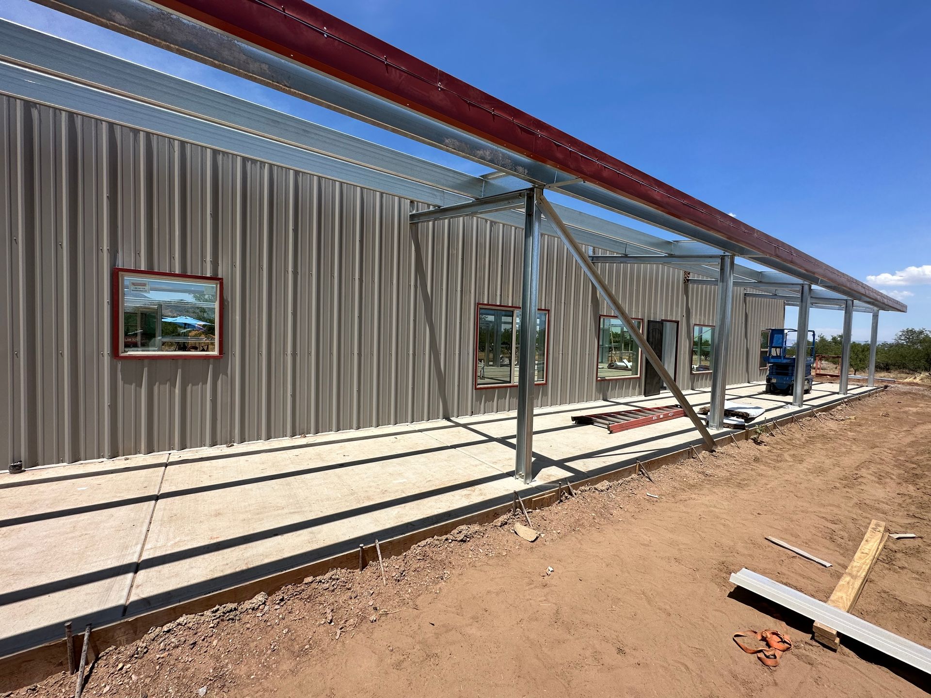A metal building is being built on a dirt road.