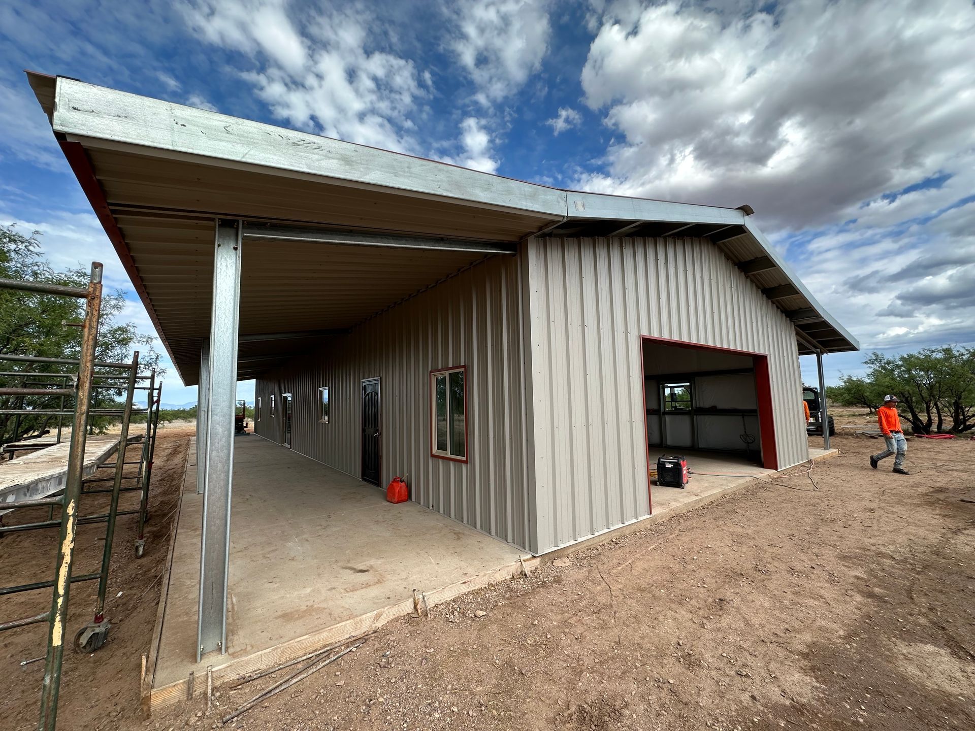 A man is walking in front of a large metal building.