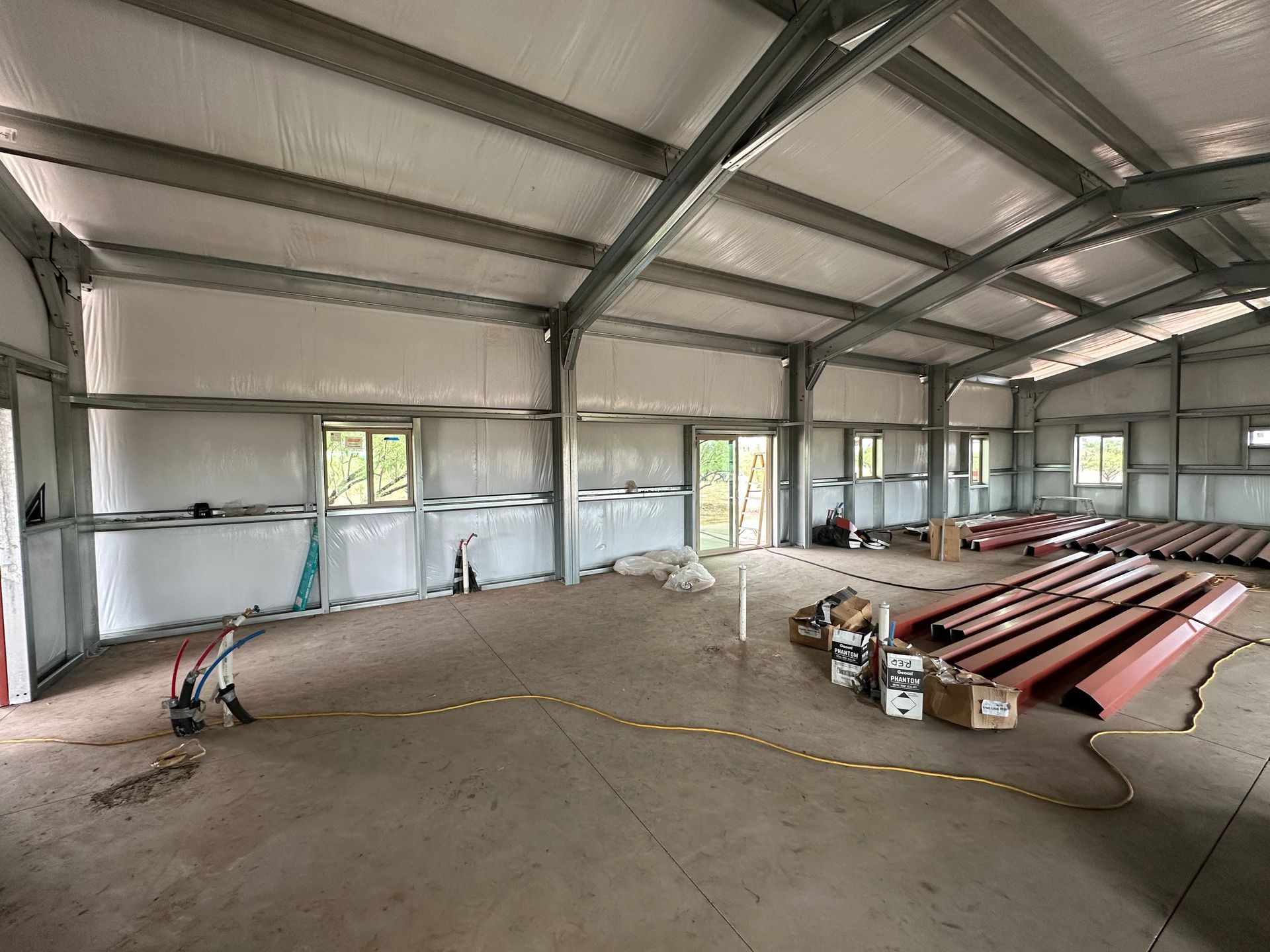 A large warehouse with a lot of pipes and boxes on the floor.