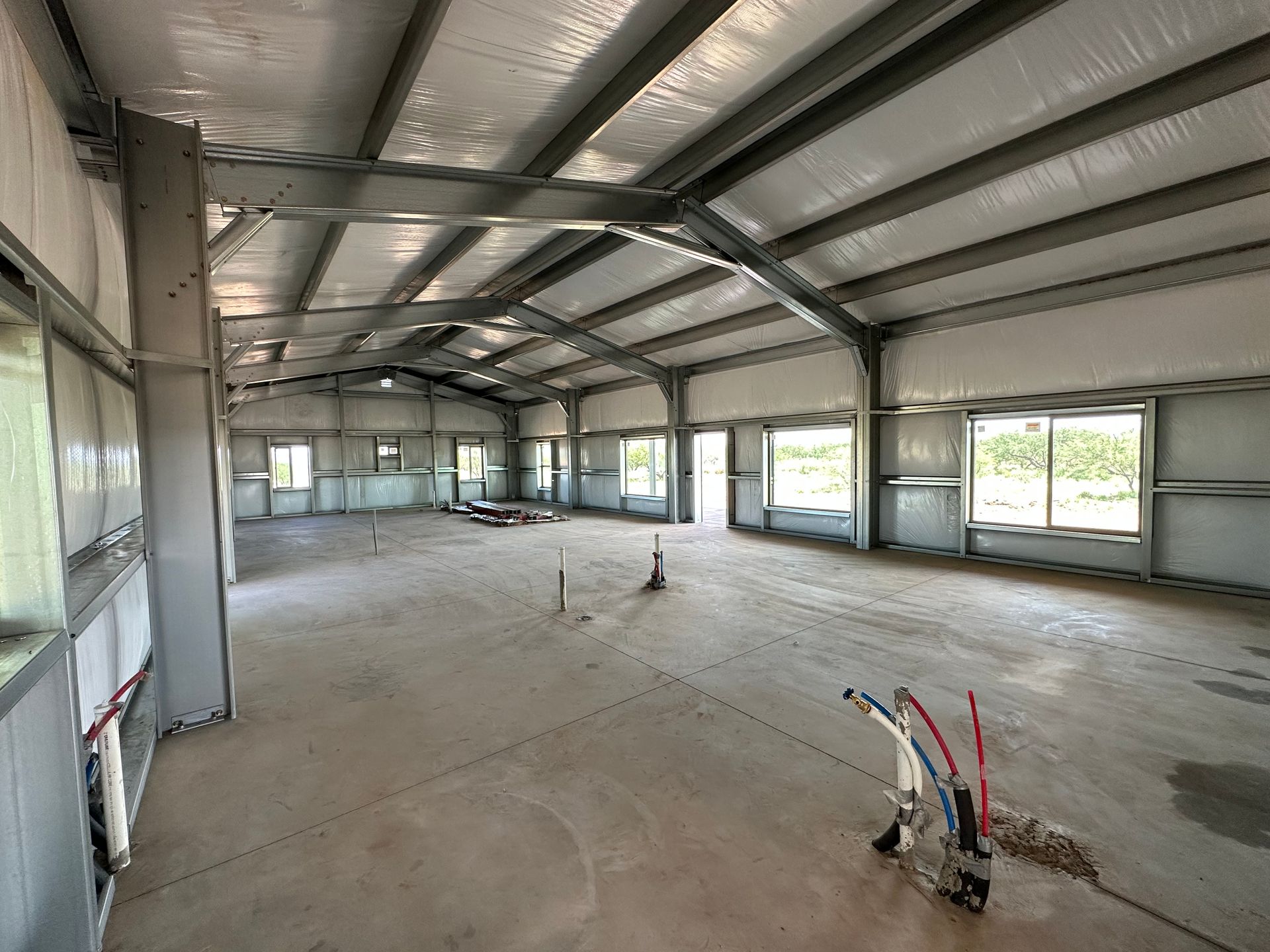 A large empty building with a lot of windows and pipes.