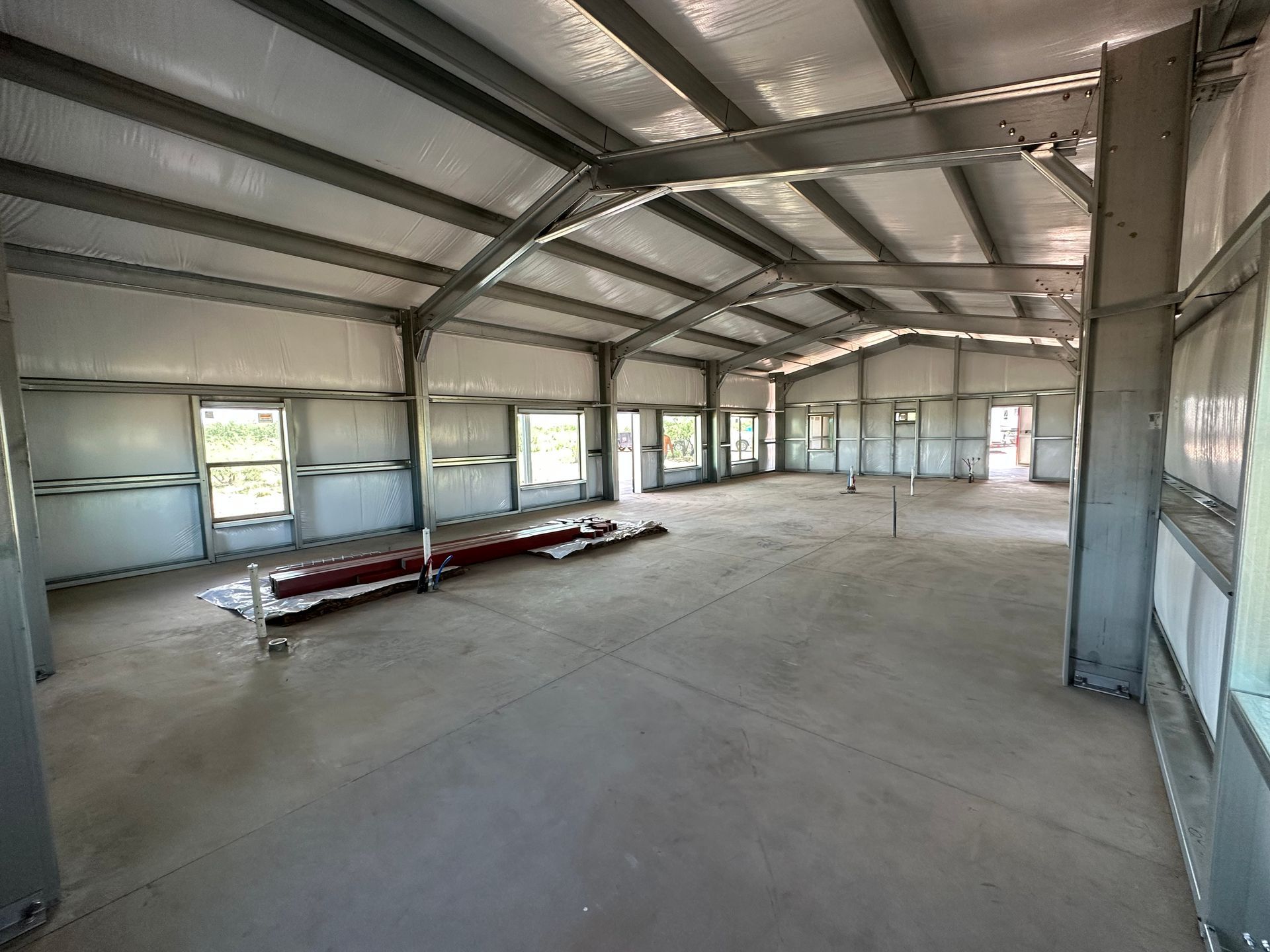 A large empty warehouse with a lot of windows and a roof.