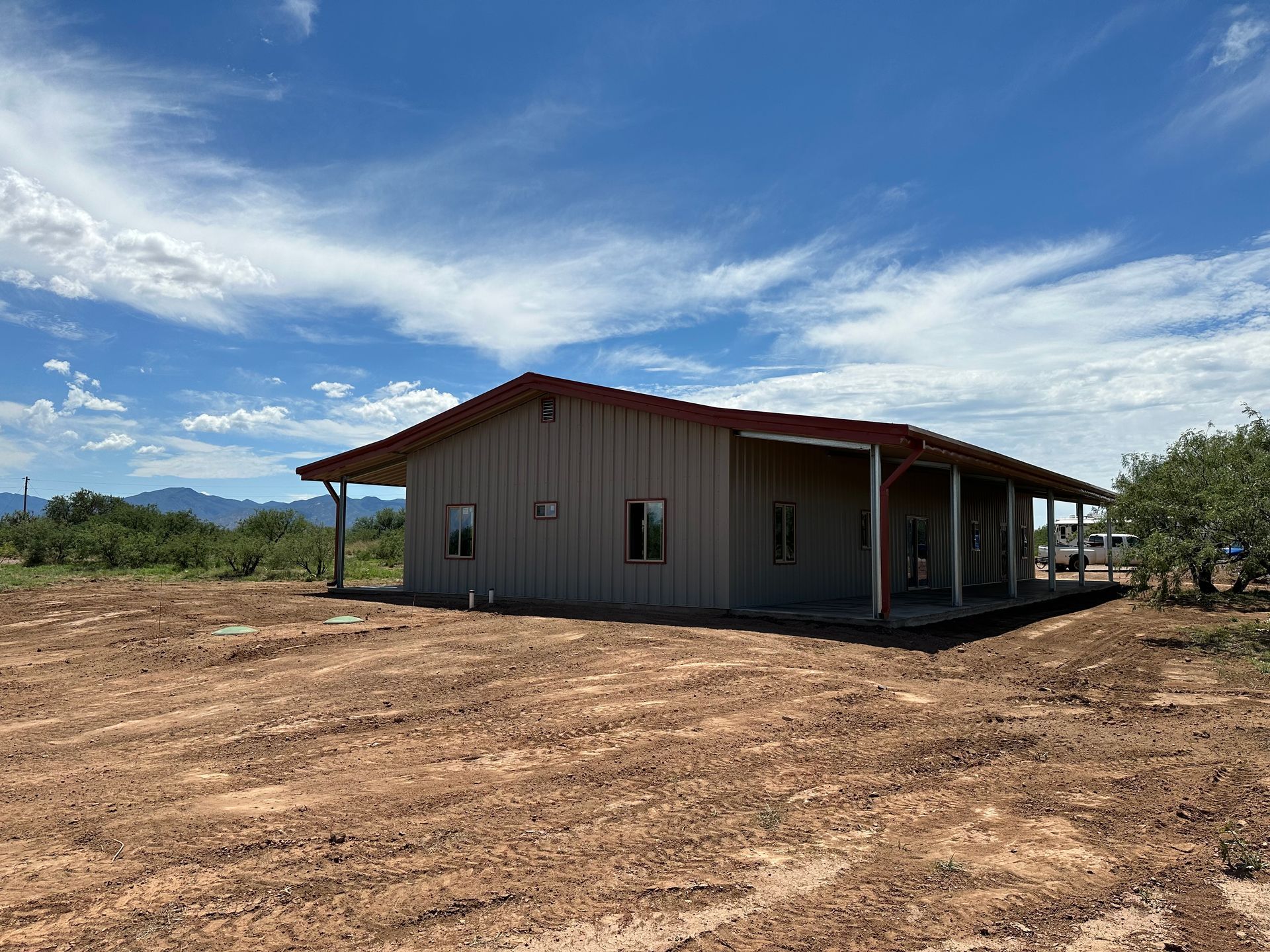 A house is sitting in the middle of a dirt field.