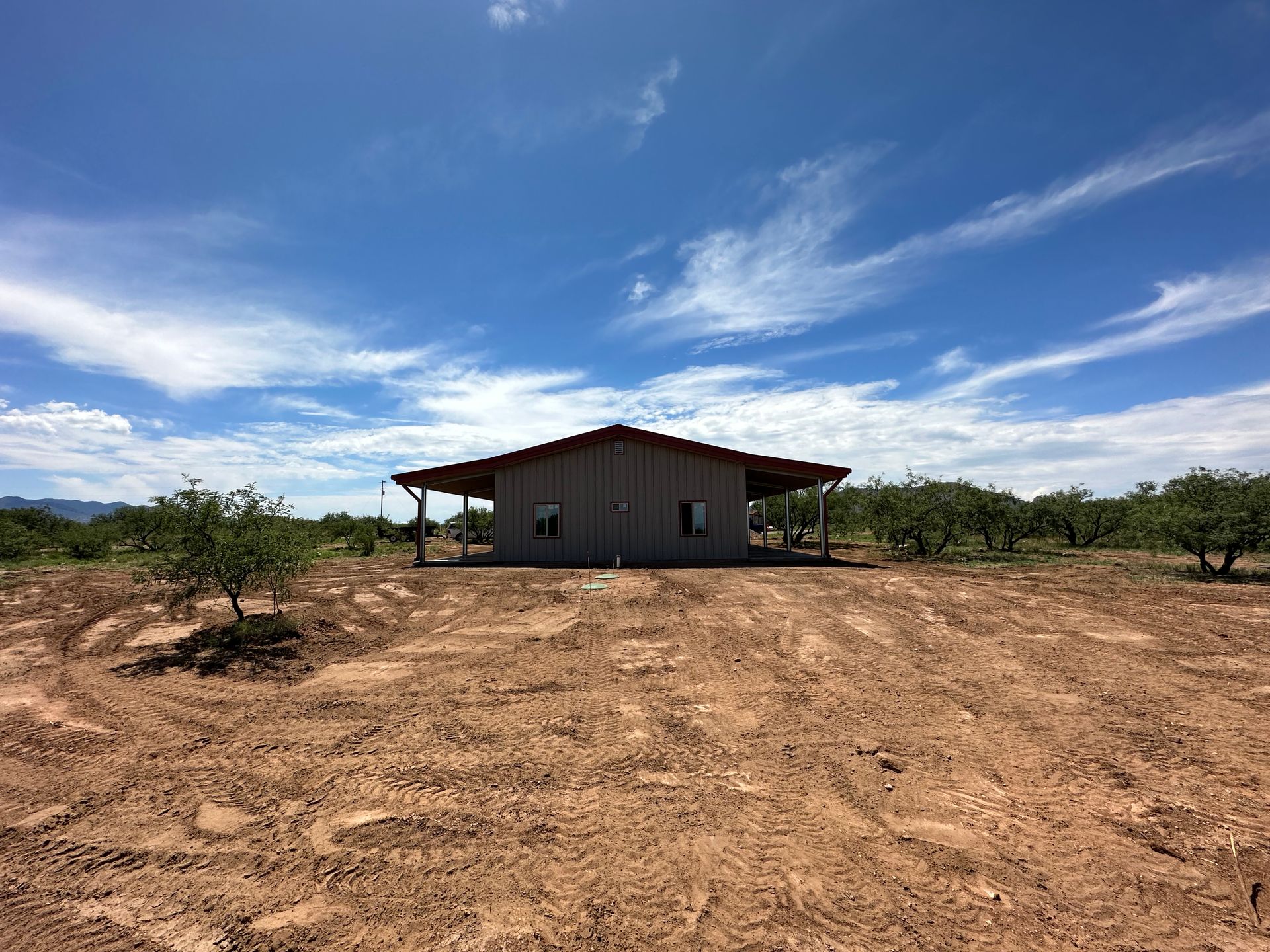 A small house is sitting in the middle of a dirt field.