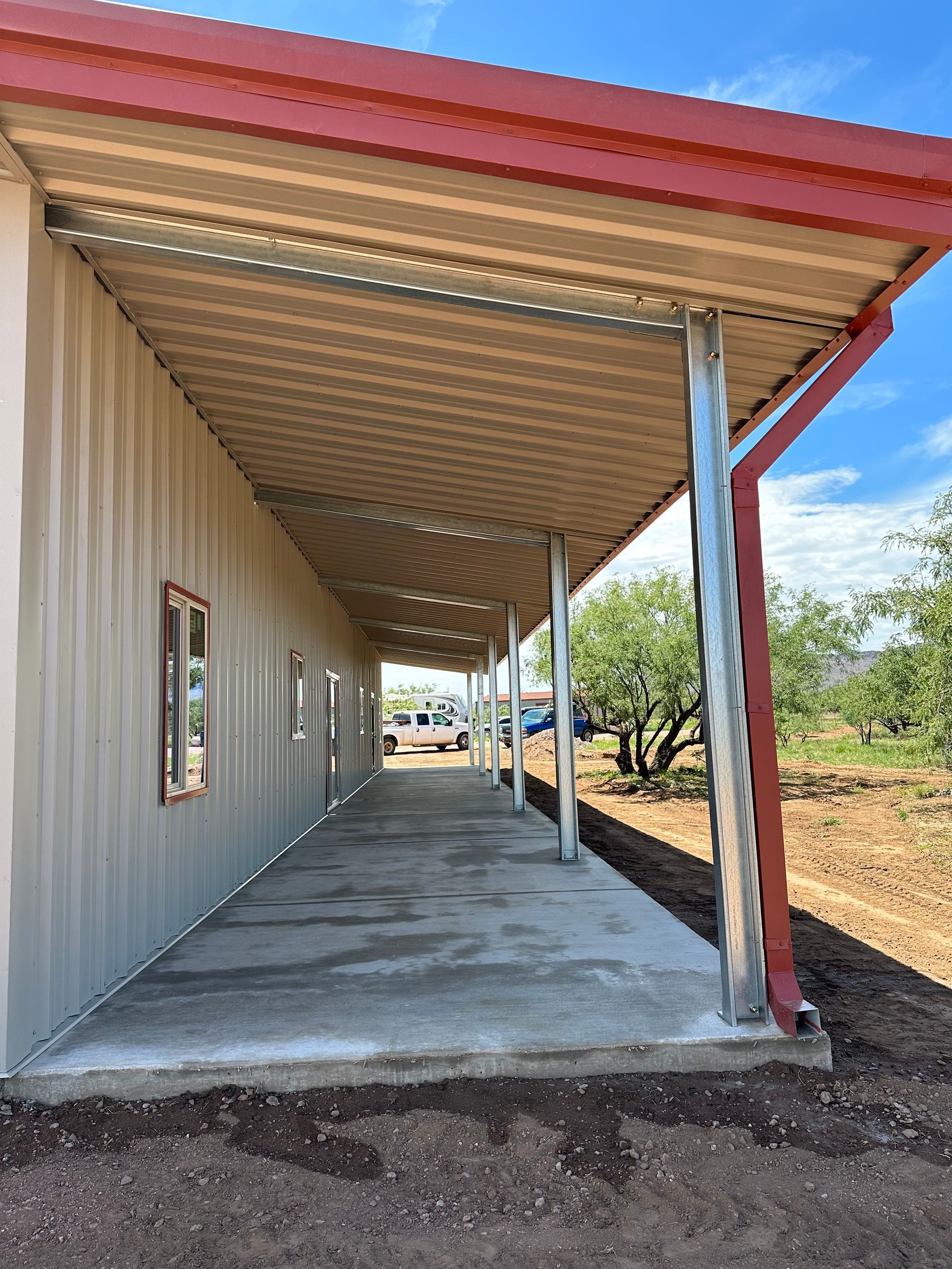 A long covered walkway leading to a building with a red roof.