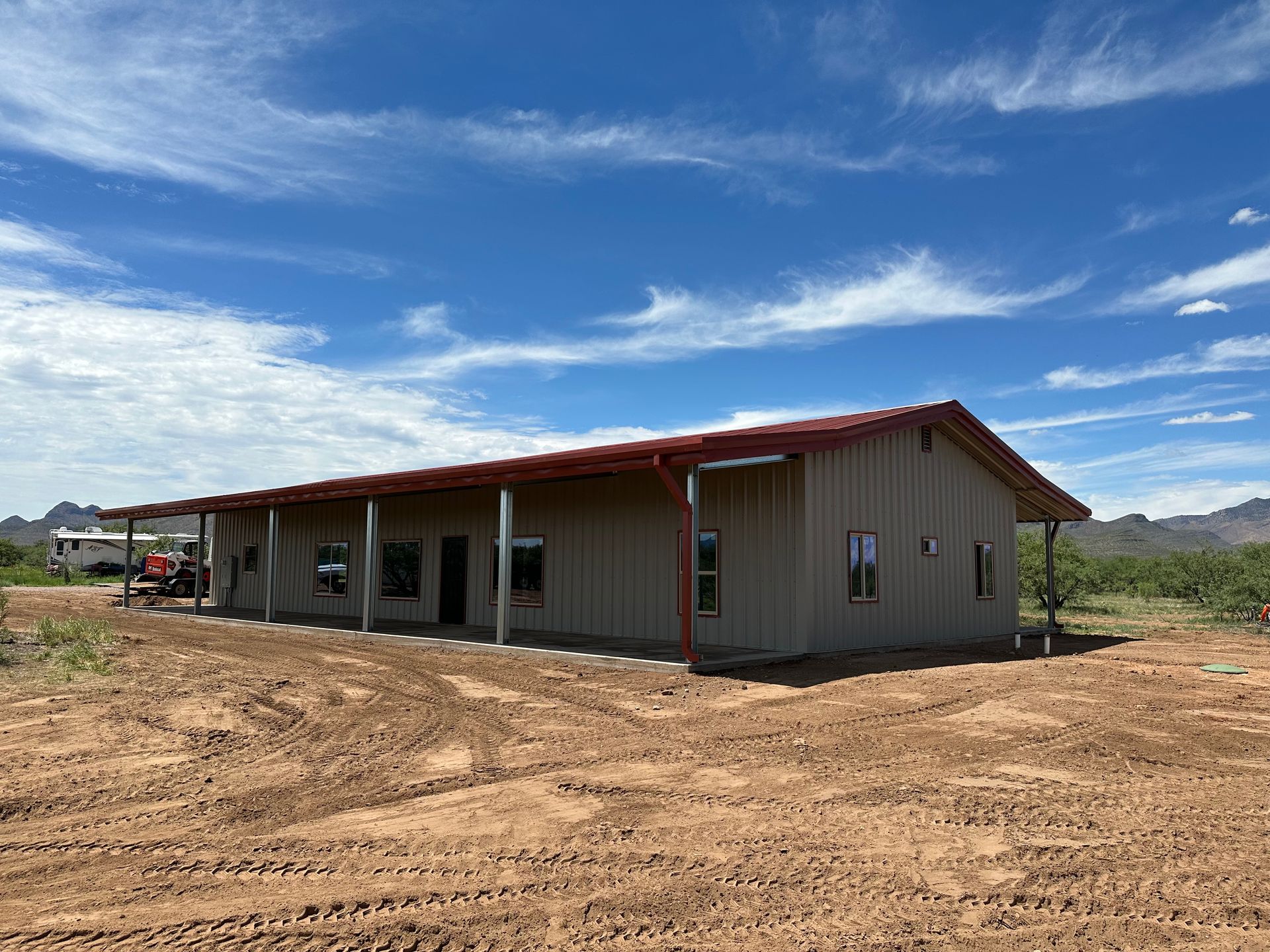 A large house is sitting in the middle of a dirt field.