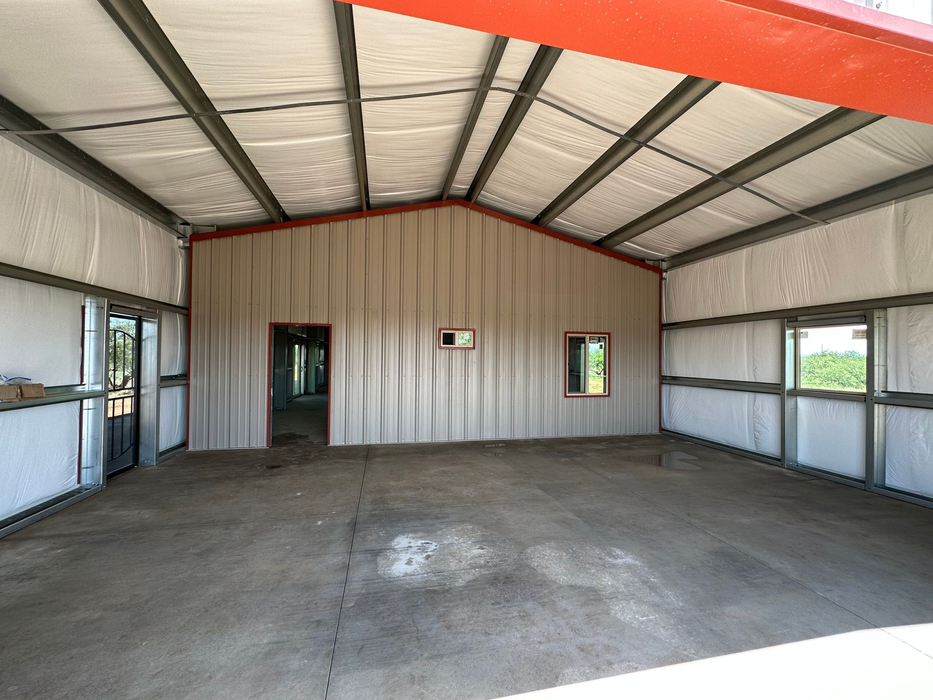 A large empty building with a red roof and white walls.