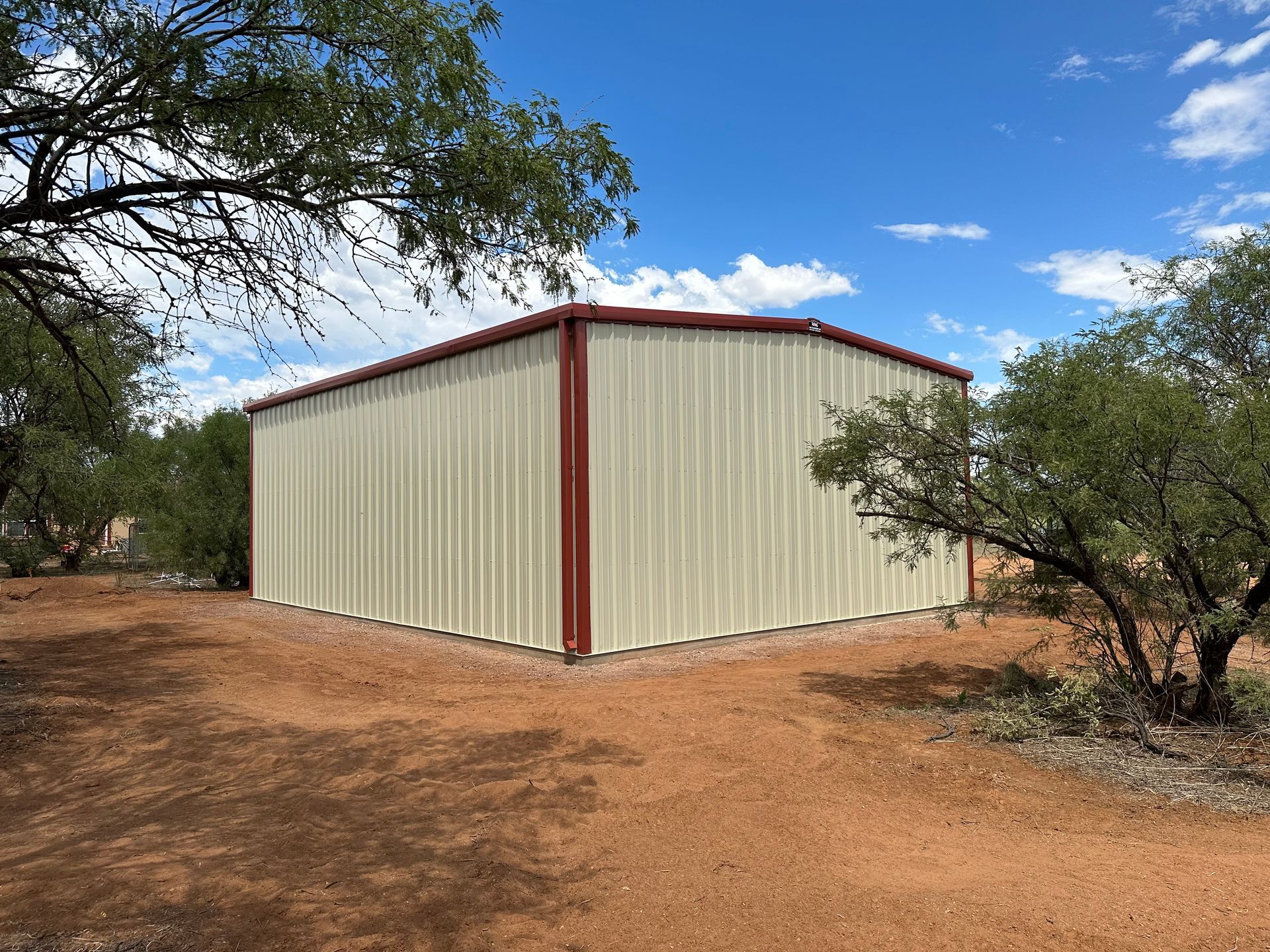 A large metal building is sitting in the middle of a dirt field.