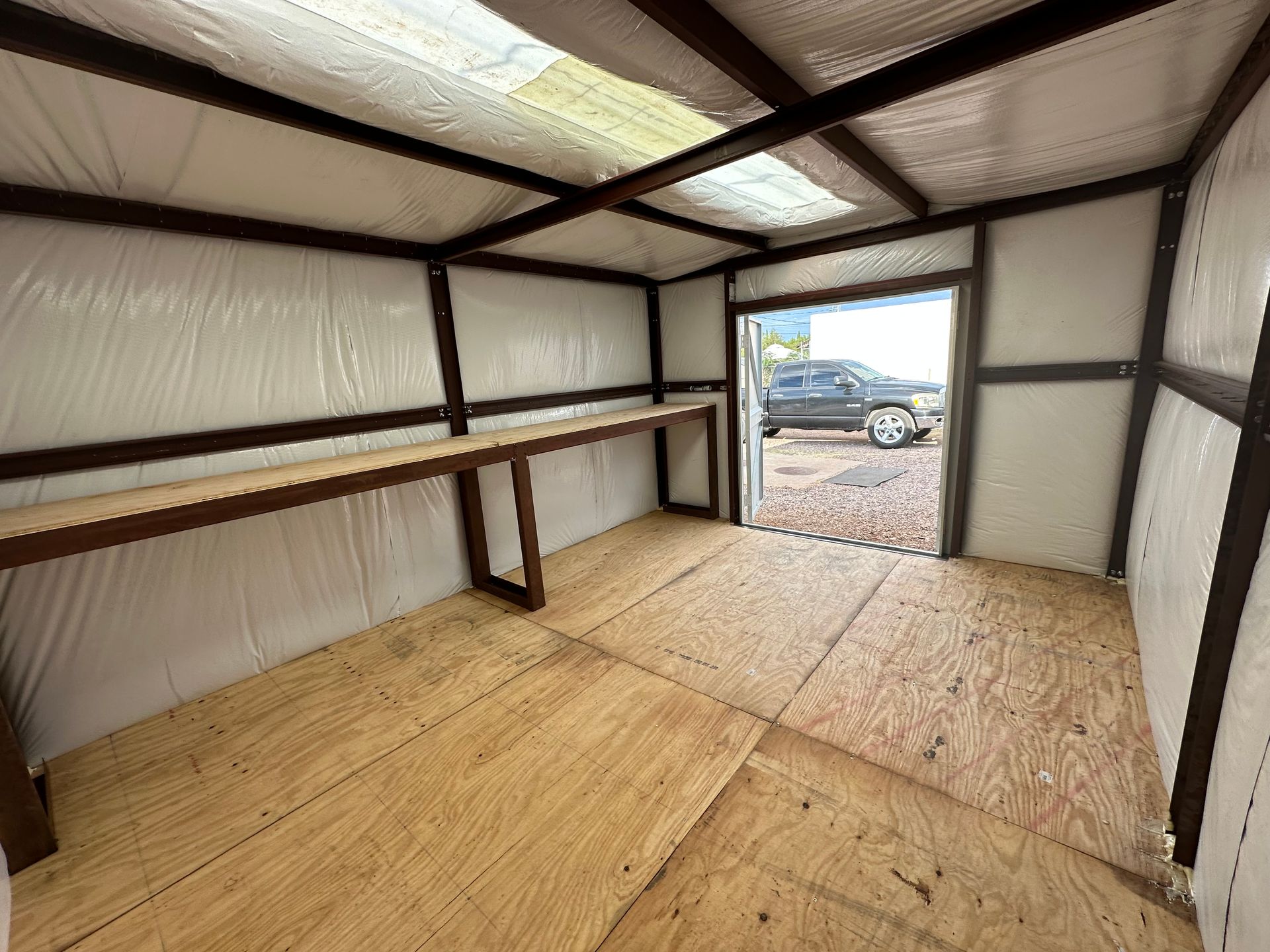 The inside of a shed with a car parked in the background.