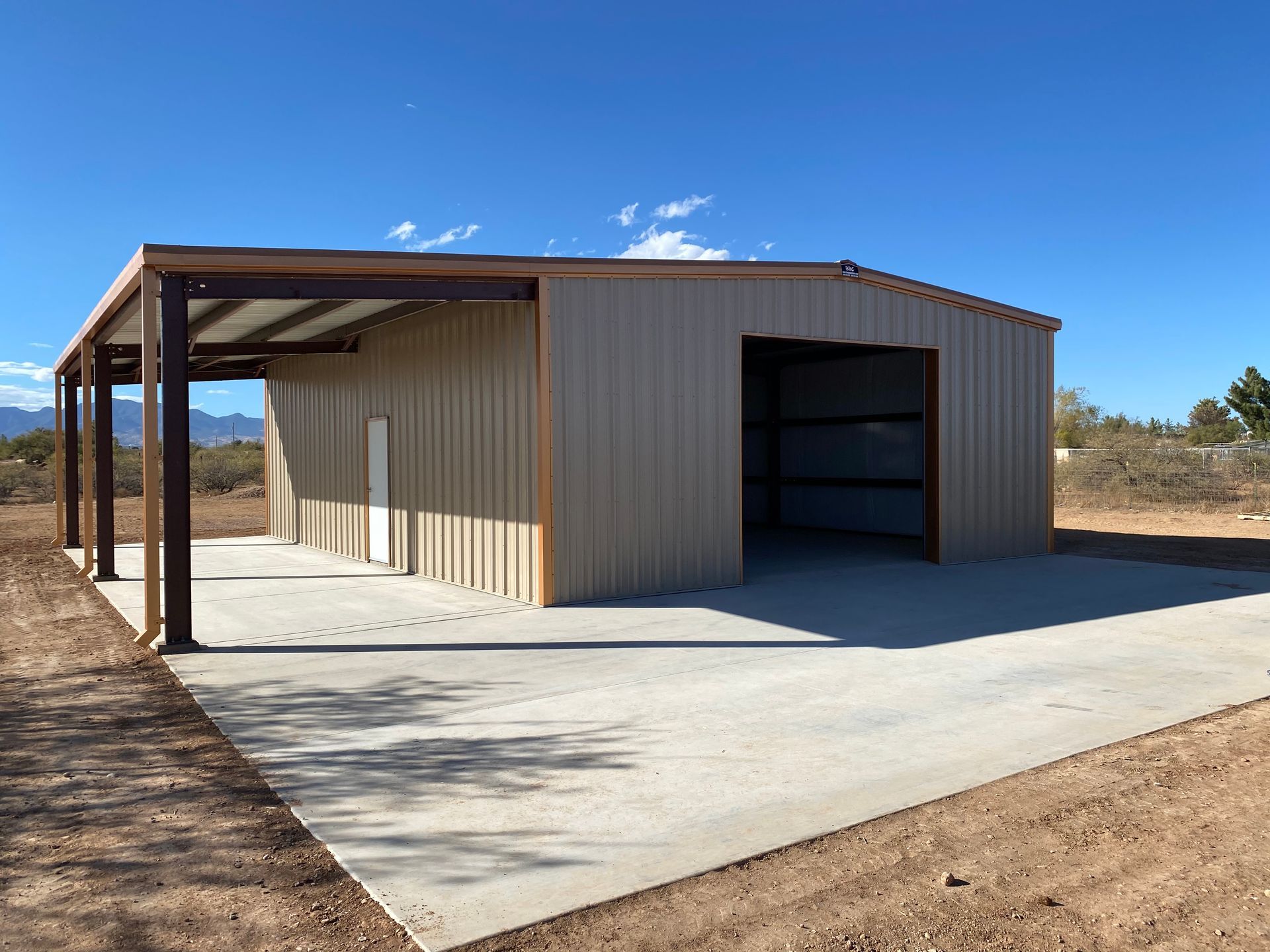 A large metal building with a concrete driveway in front of it