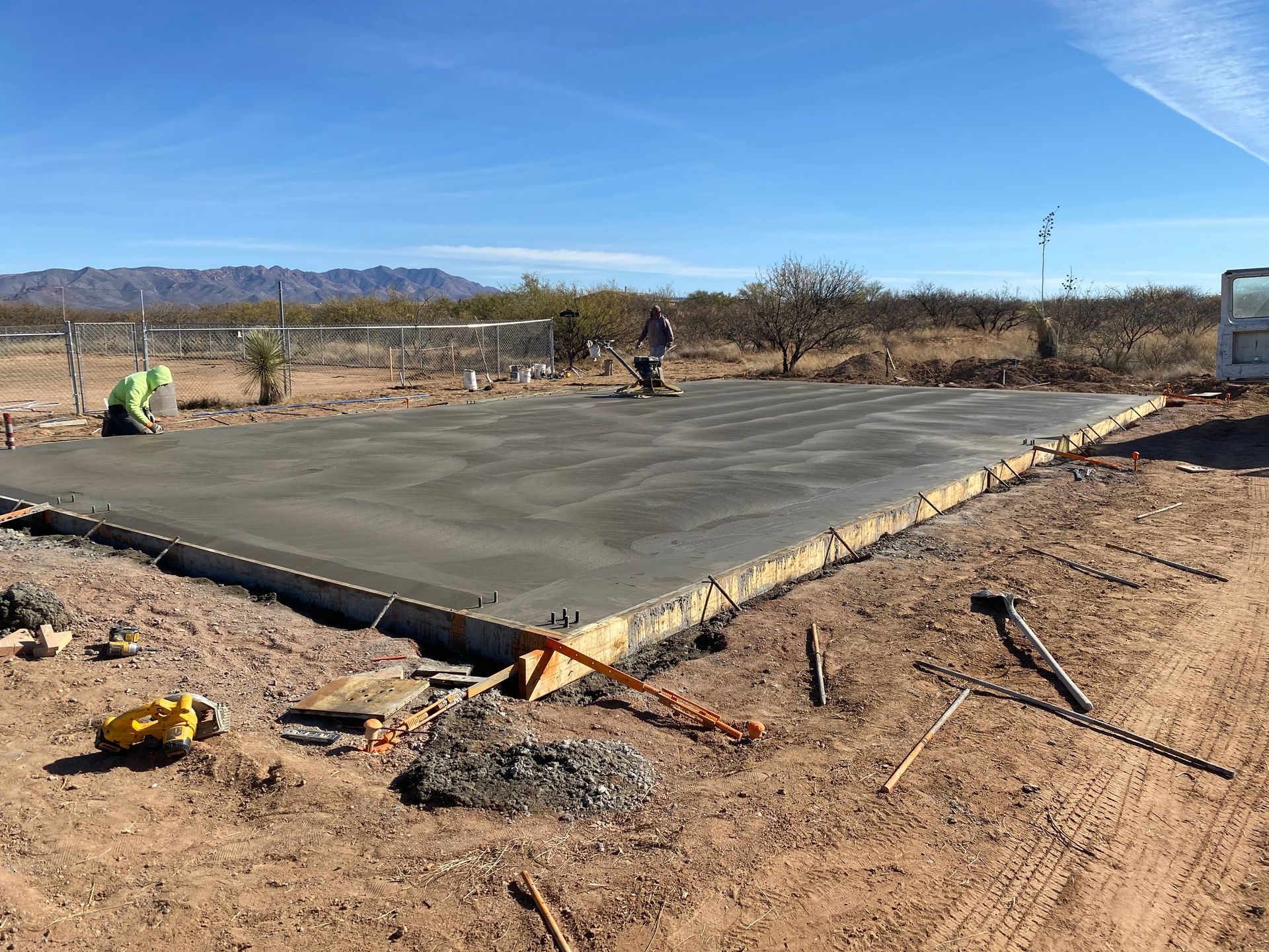 A large concrete slab is being built in the middle of a dirt field.