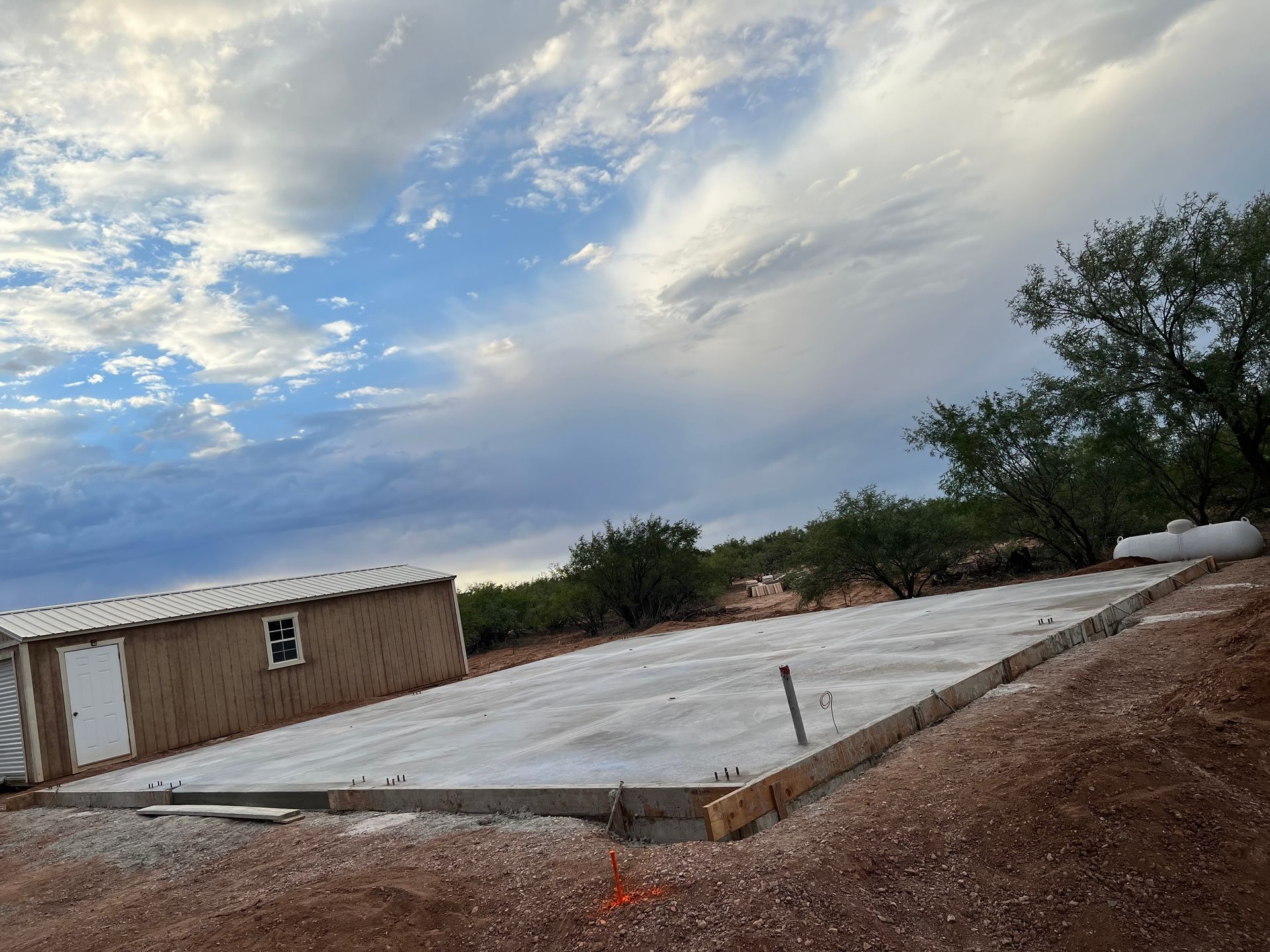A concrete base for a house is being built in the middle of a dirt field.