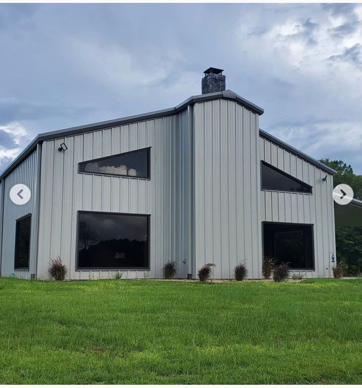 A large house with a lot of windows is sitting on top of a lush green field.