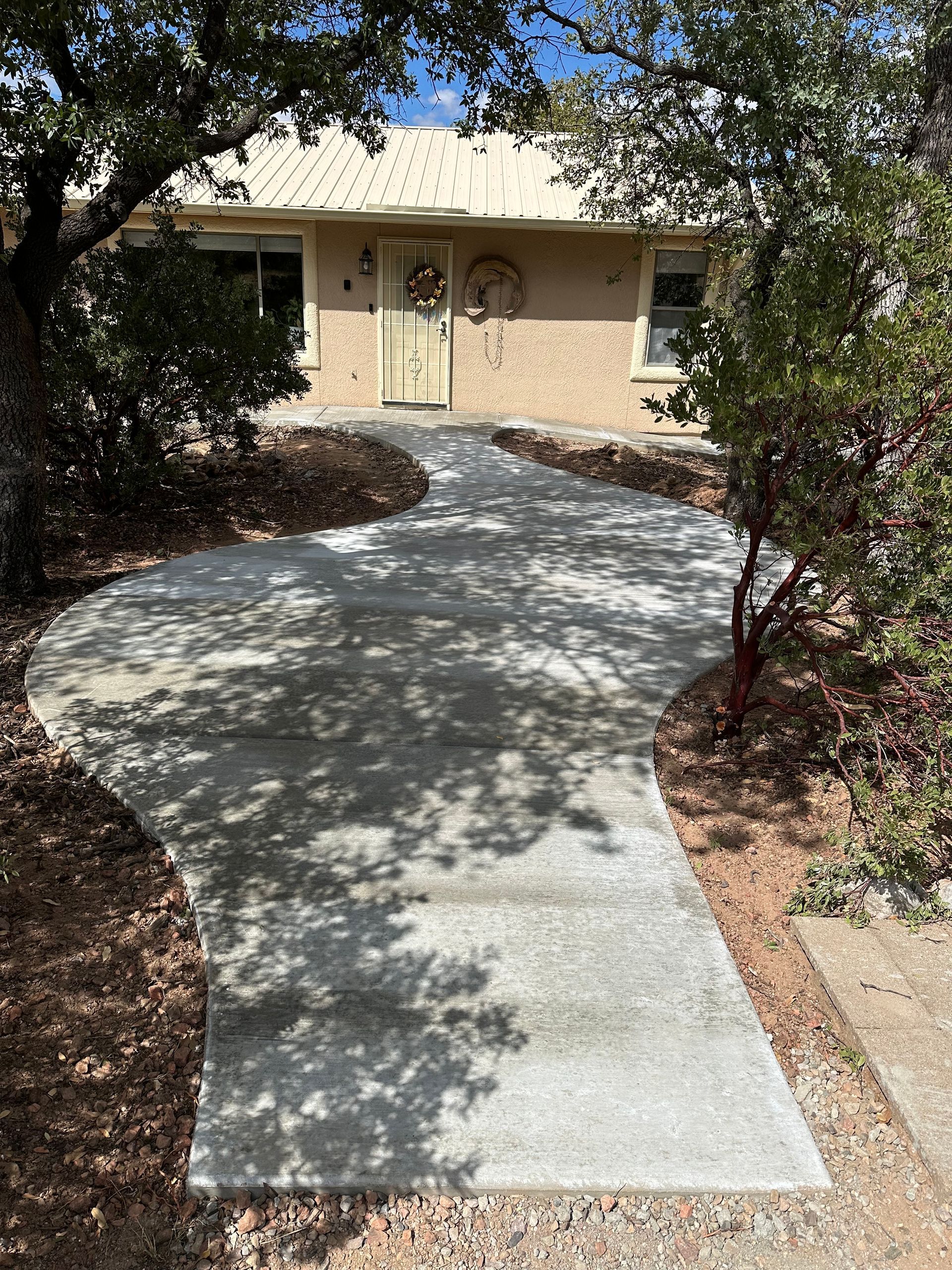 A concrete walkway leading to a house with a wreath on the door.