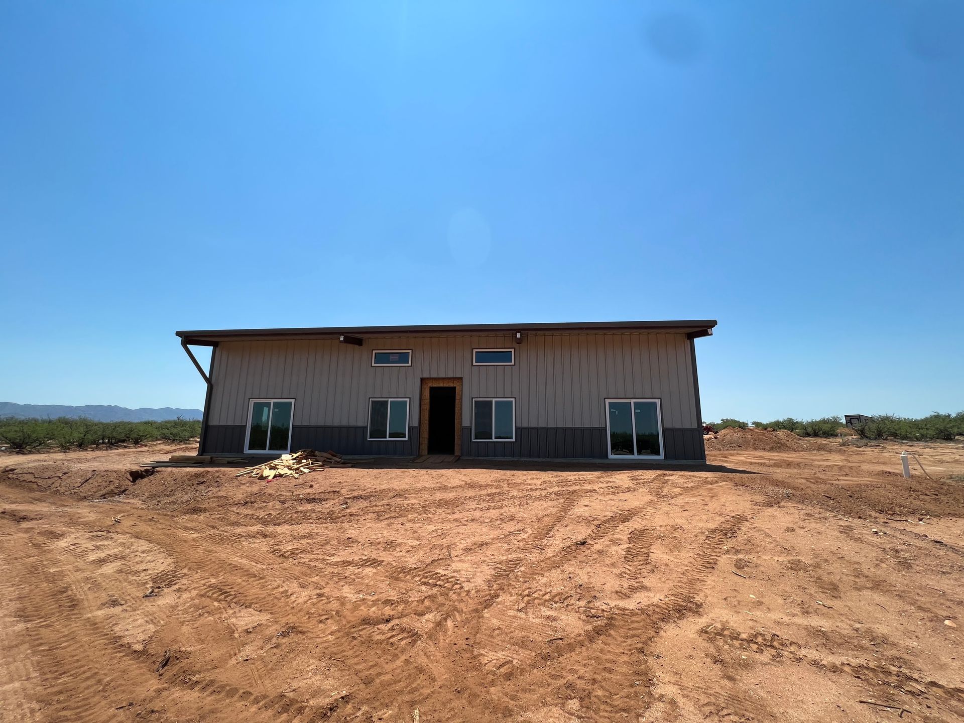 A large house is sitting in the middle of a dirt field.