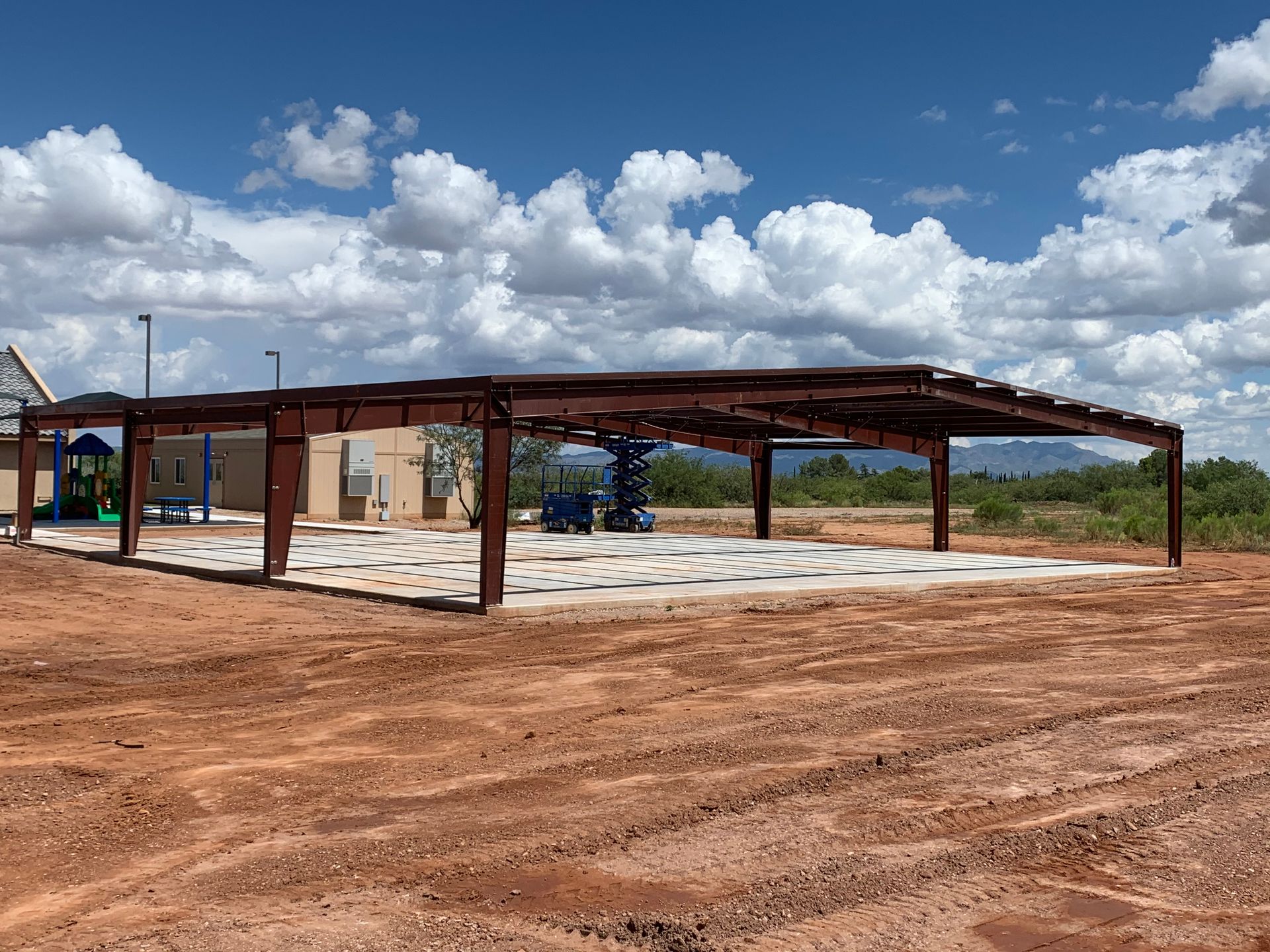 A large metal structure is sitting in the middle of a dirt field.
