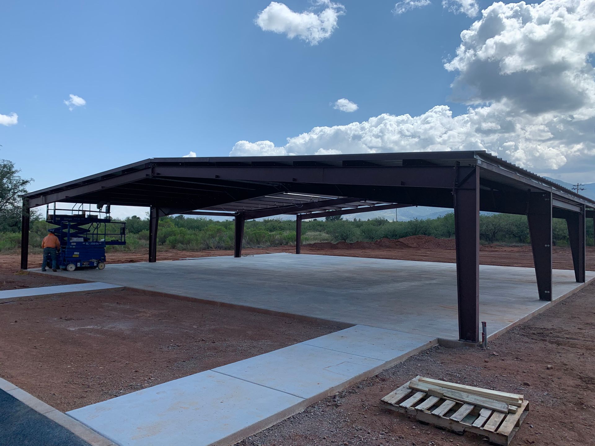 A large metal structure is being built in the middle of a dirt field.