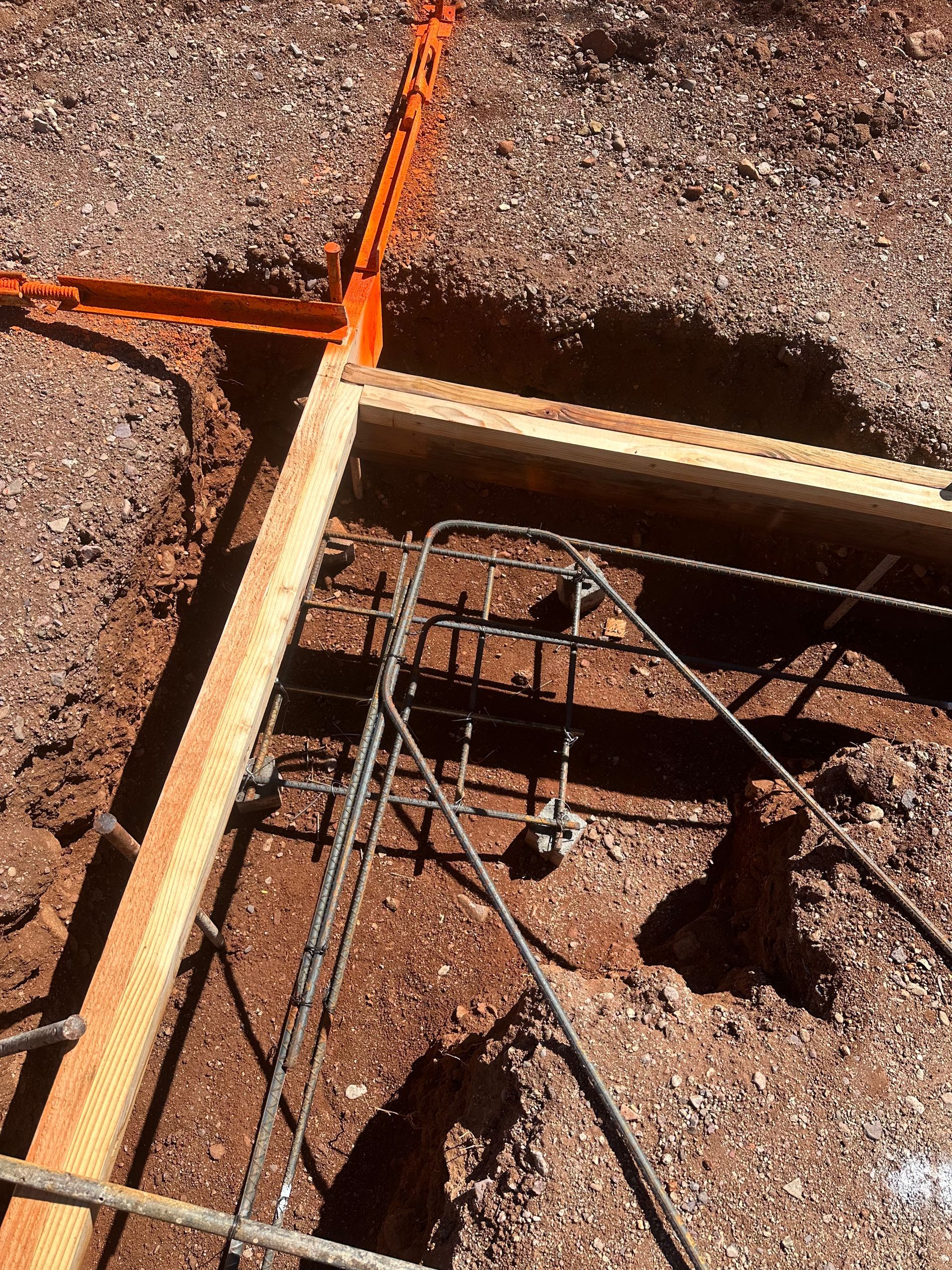 A wooden frame is sitting in the dirt next to a metal frame.