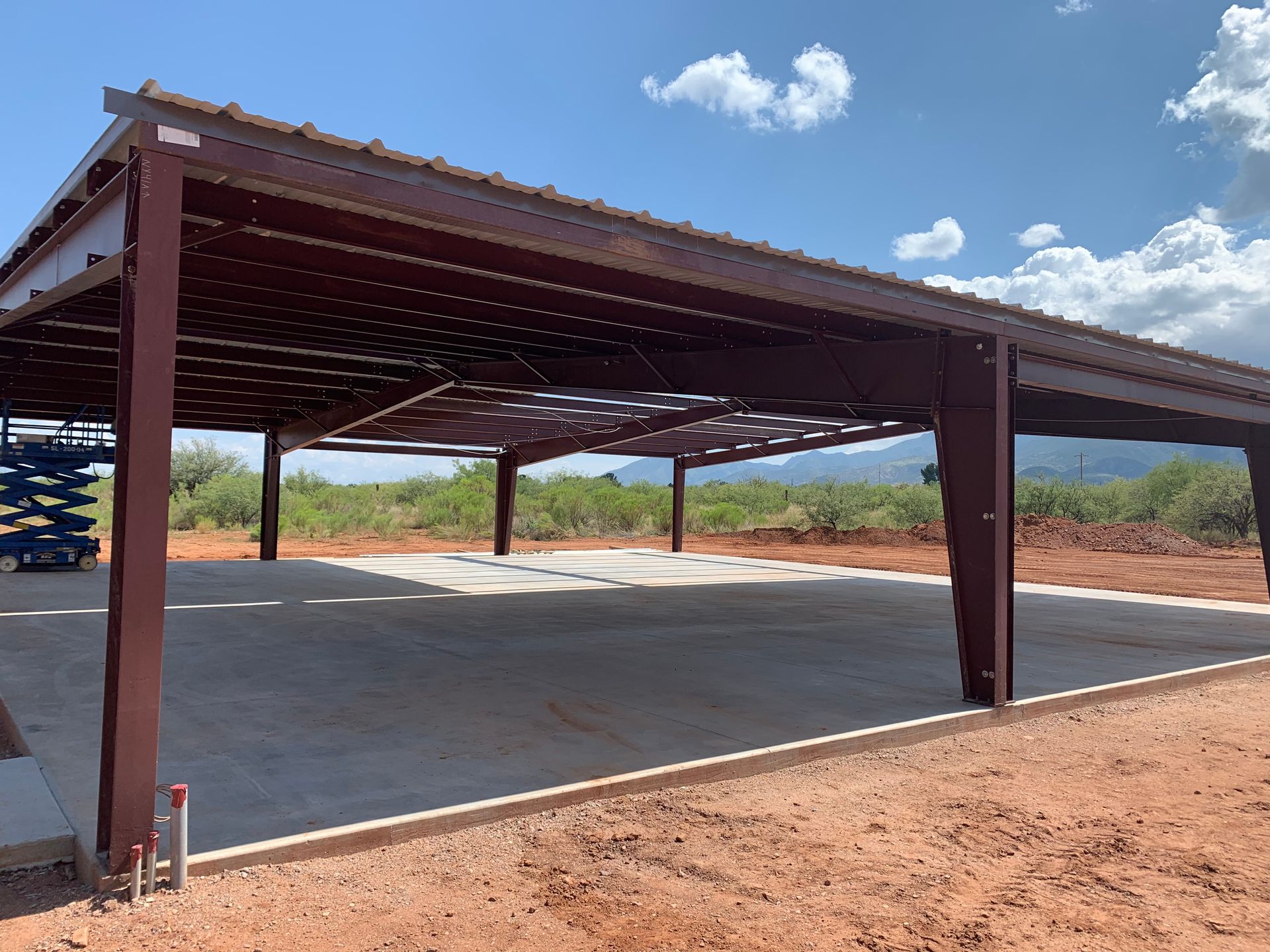 A large metal structure is being built in the middle of a dirt field.