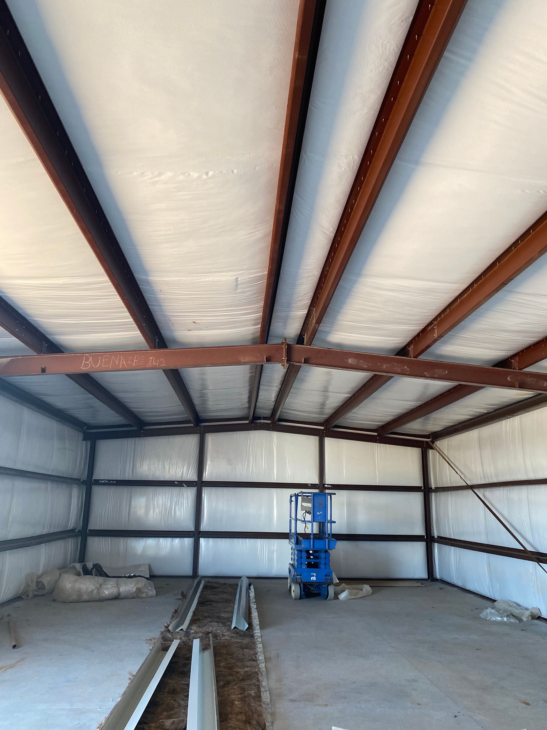 A blue lift is sitting inside of a metal building.