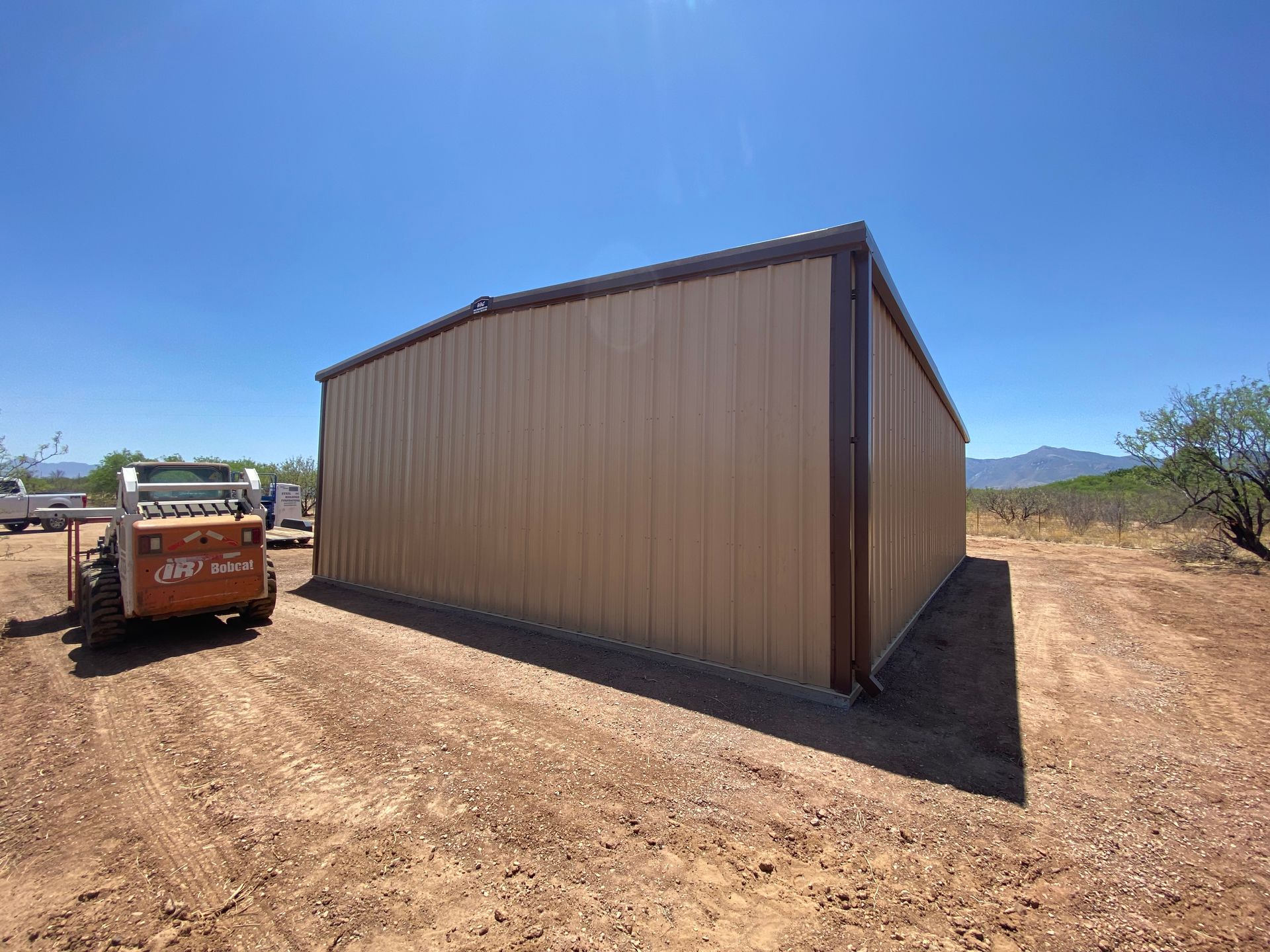 A large metal building with a bulldozer parked in front of it.