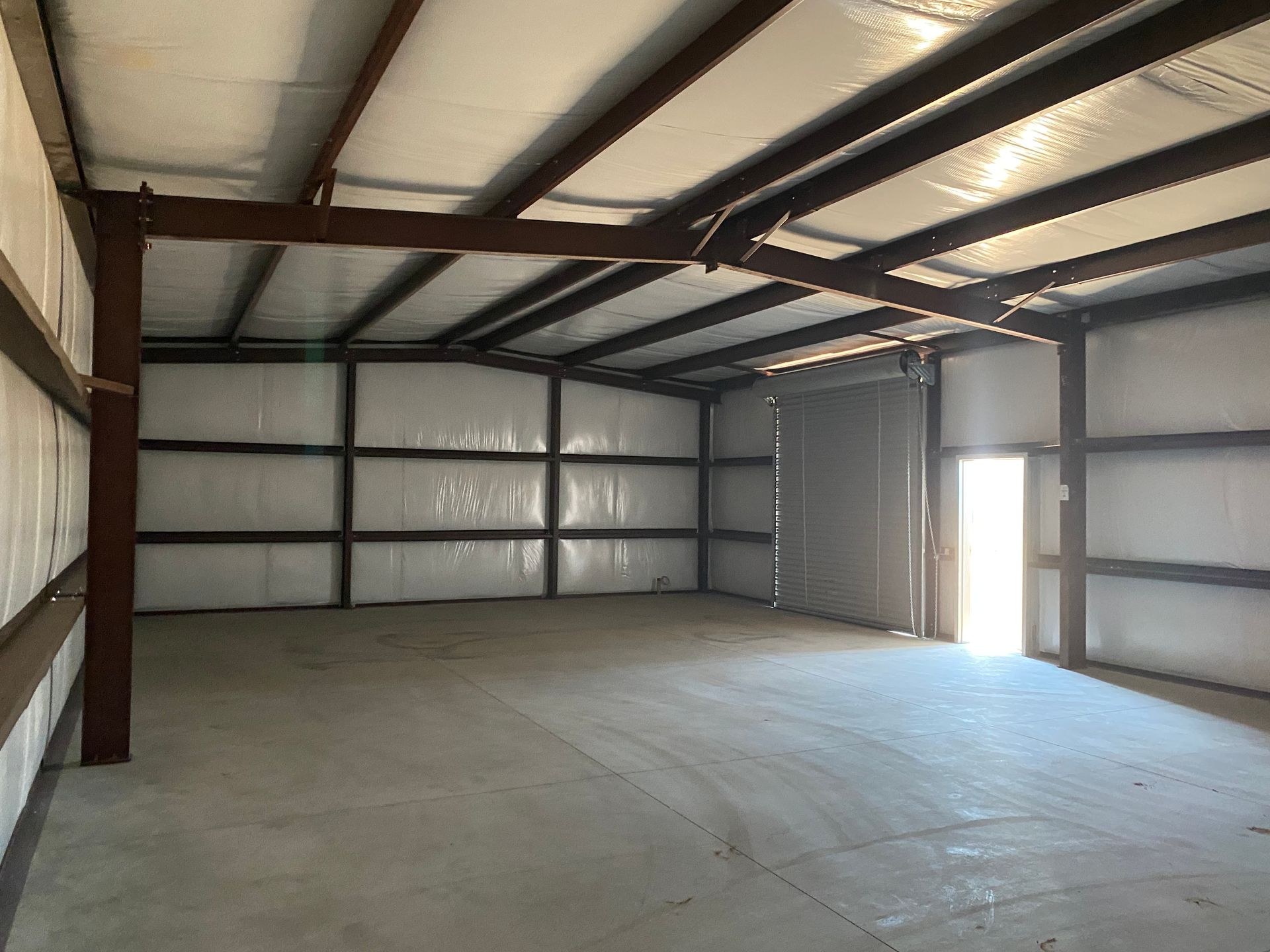 A large empty warehouse with a metal roof and a door.