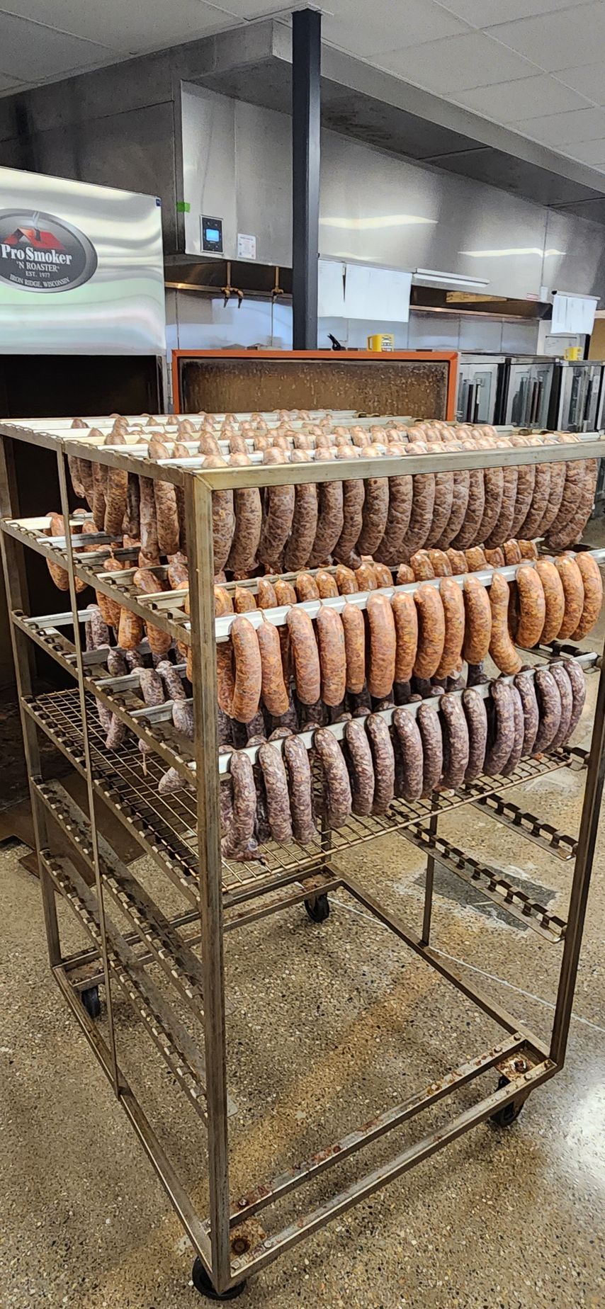 A bunch of sausages are hanging on a rack in a butcher shop.