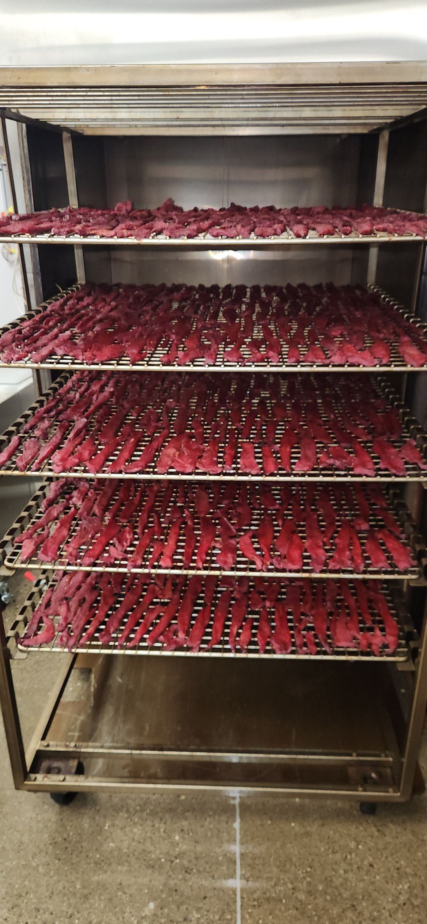 A stainless steel rack filled with lots of red meat.