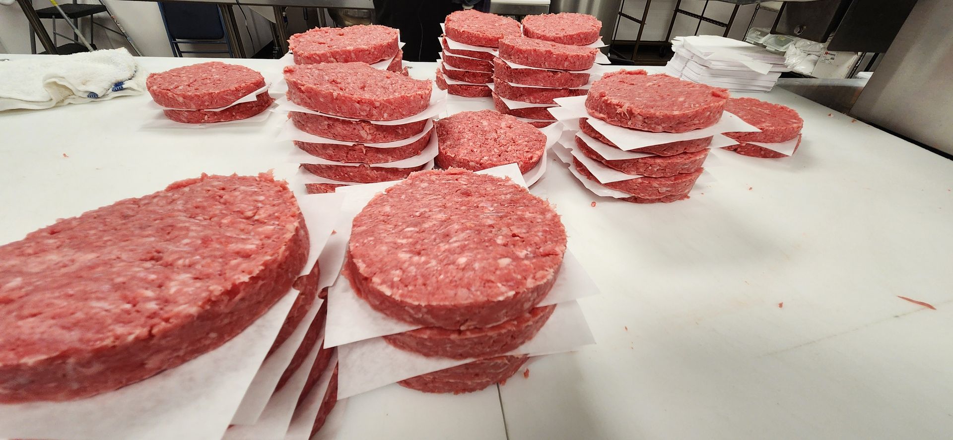 A bunch of hamburger patties are stacked on top of each other on a table.
