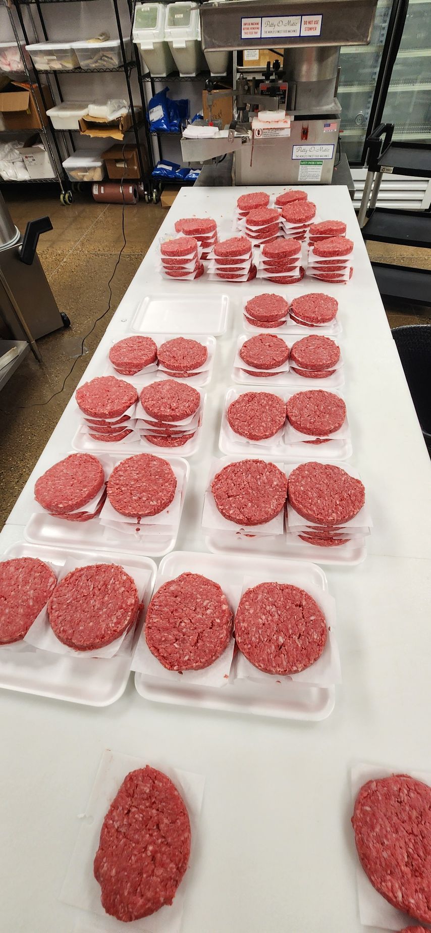 A bunch of hamburger patties are sitting on a table.