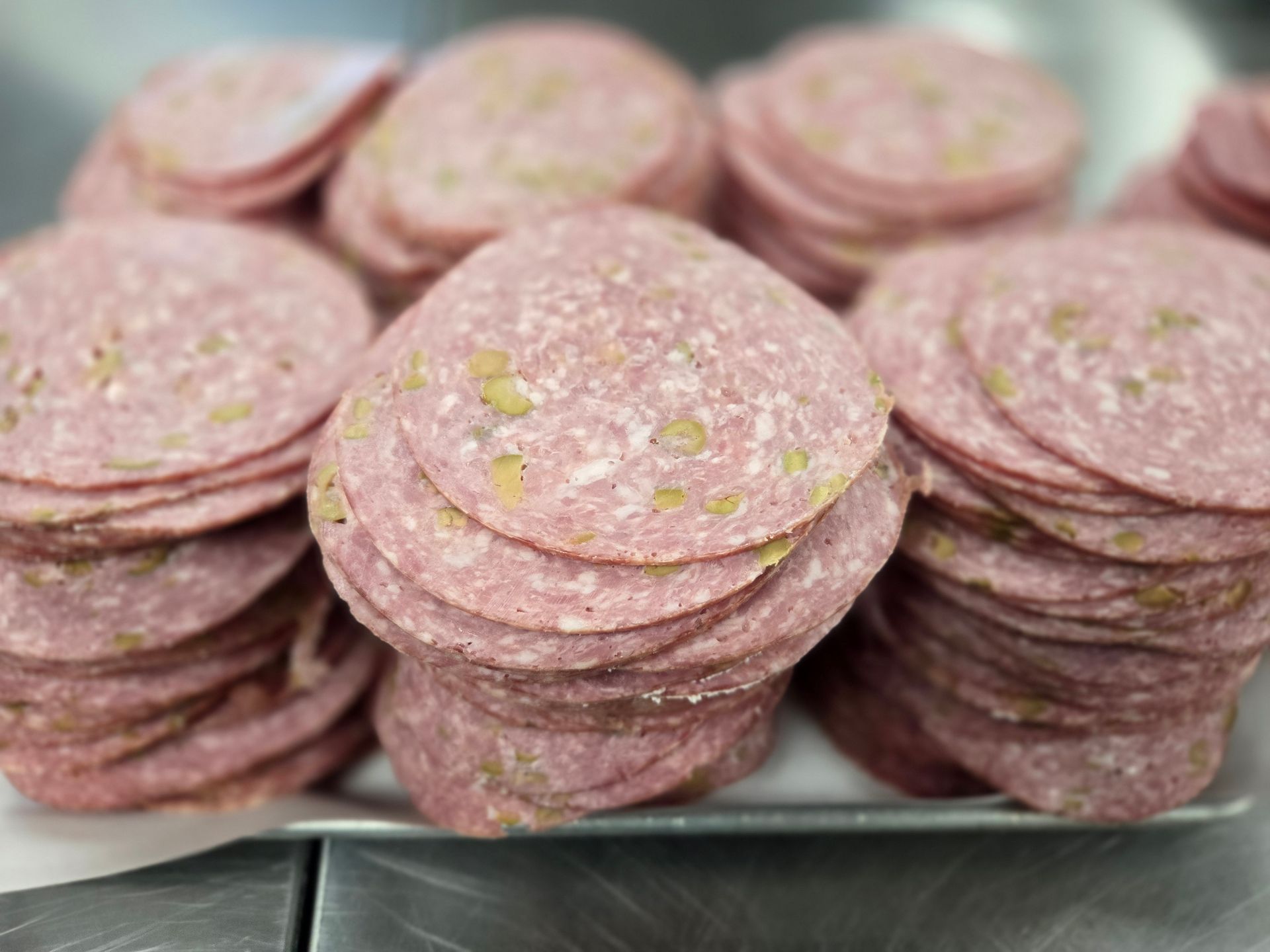 A tray of salami slices stacked on top of each other on a table.