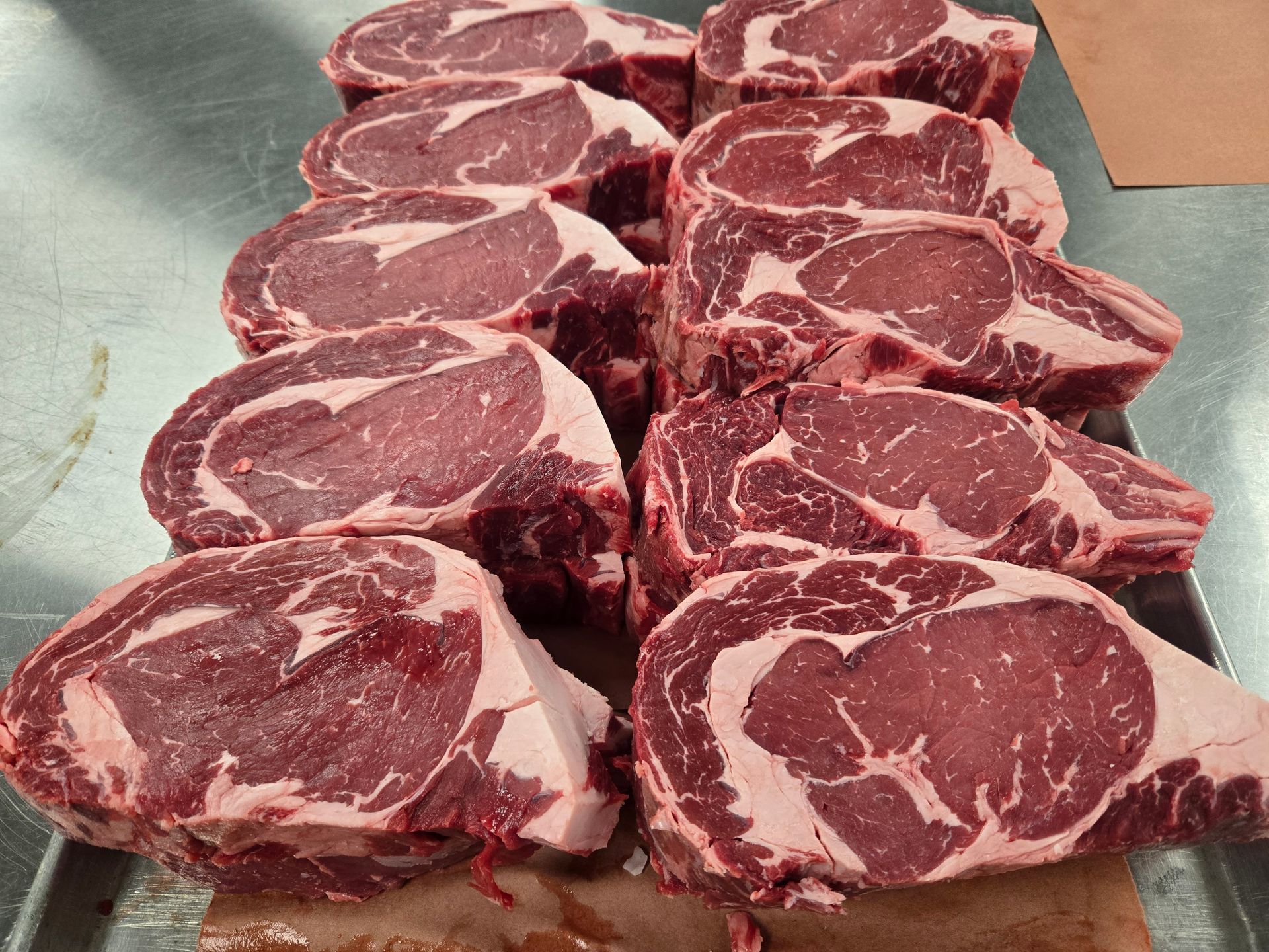 A bunch of raw steaks are sitting on a tray on a table.