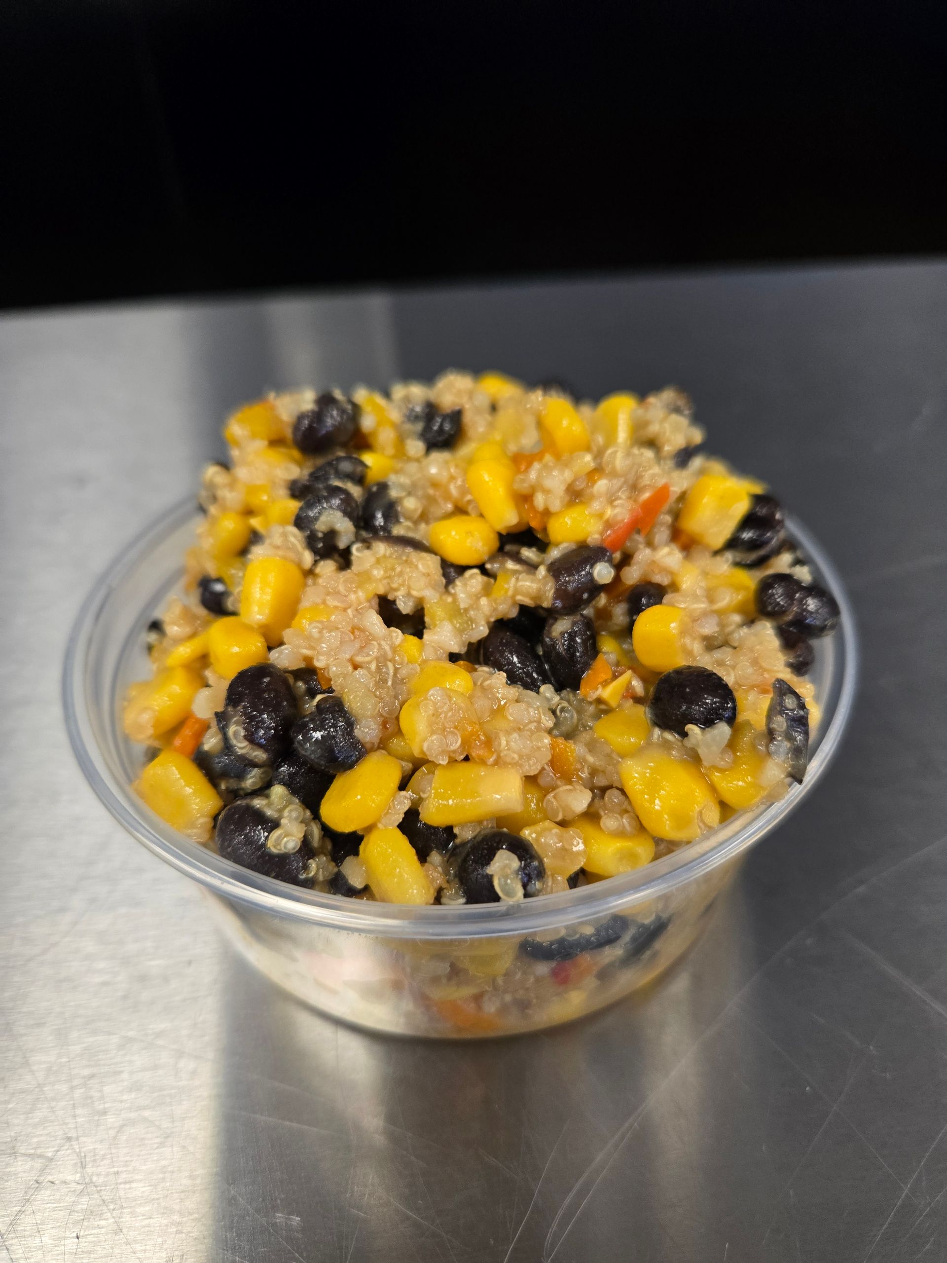 A plastic bowl filled with corn , black beans and rice