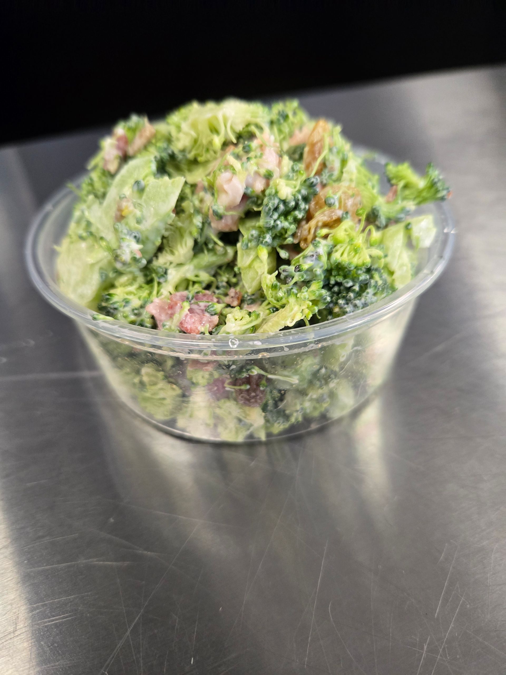 A close up of a salad in a plastic container on a table.