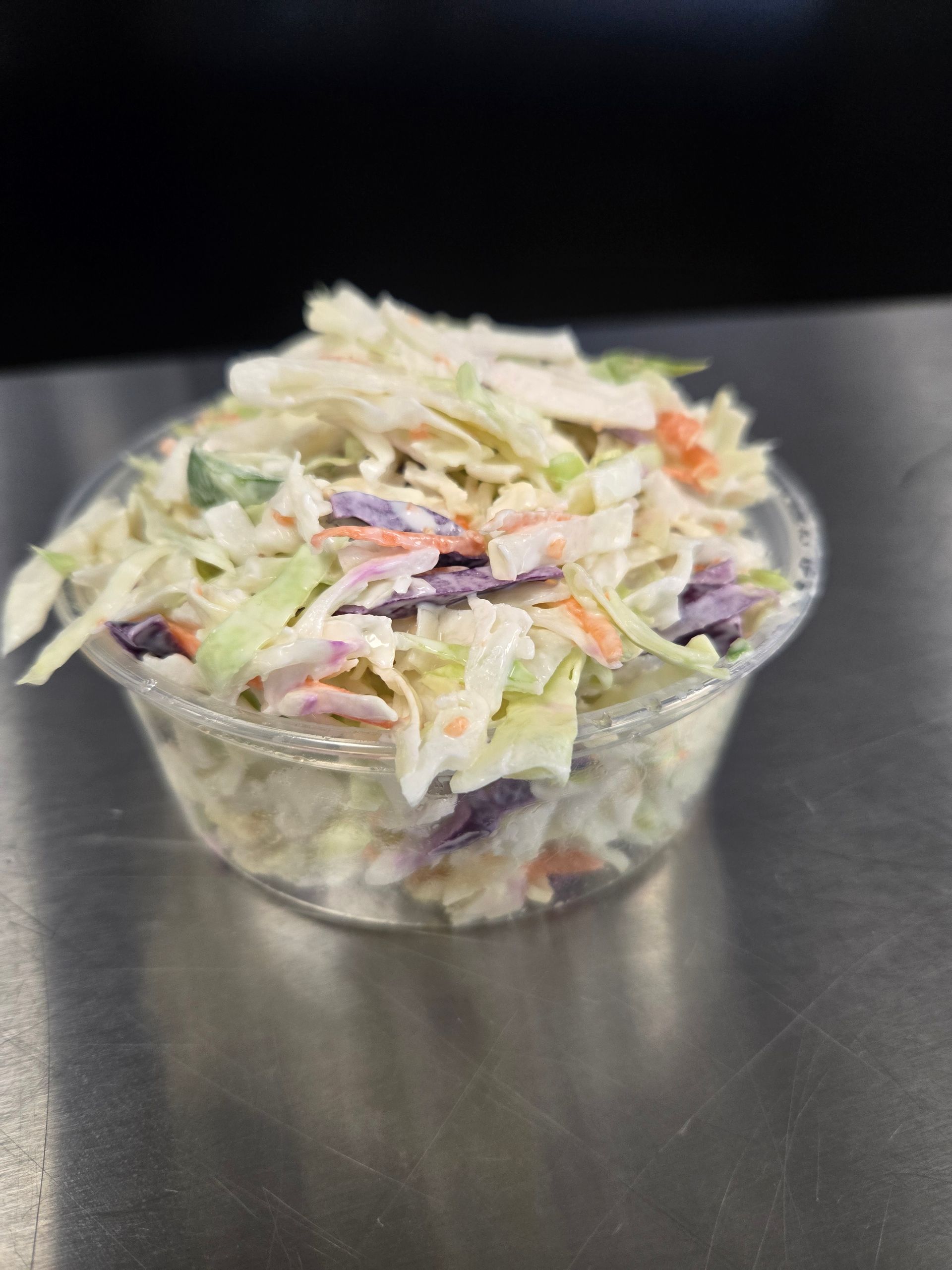 A close up of a bowl of coleslaw on a table.