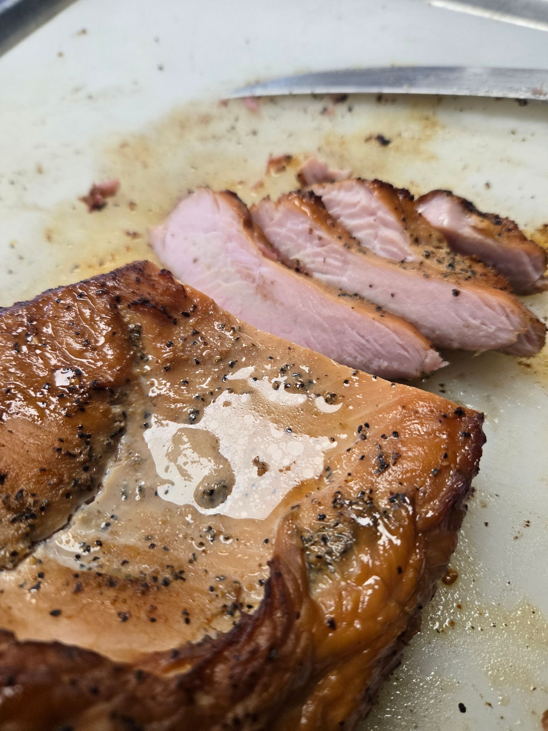 A piece of meat is being sliced on a cutting board
