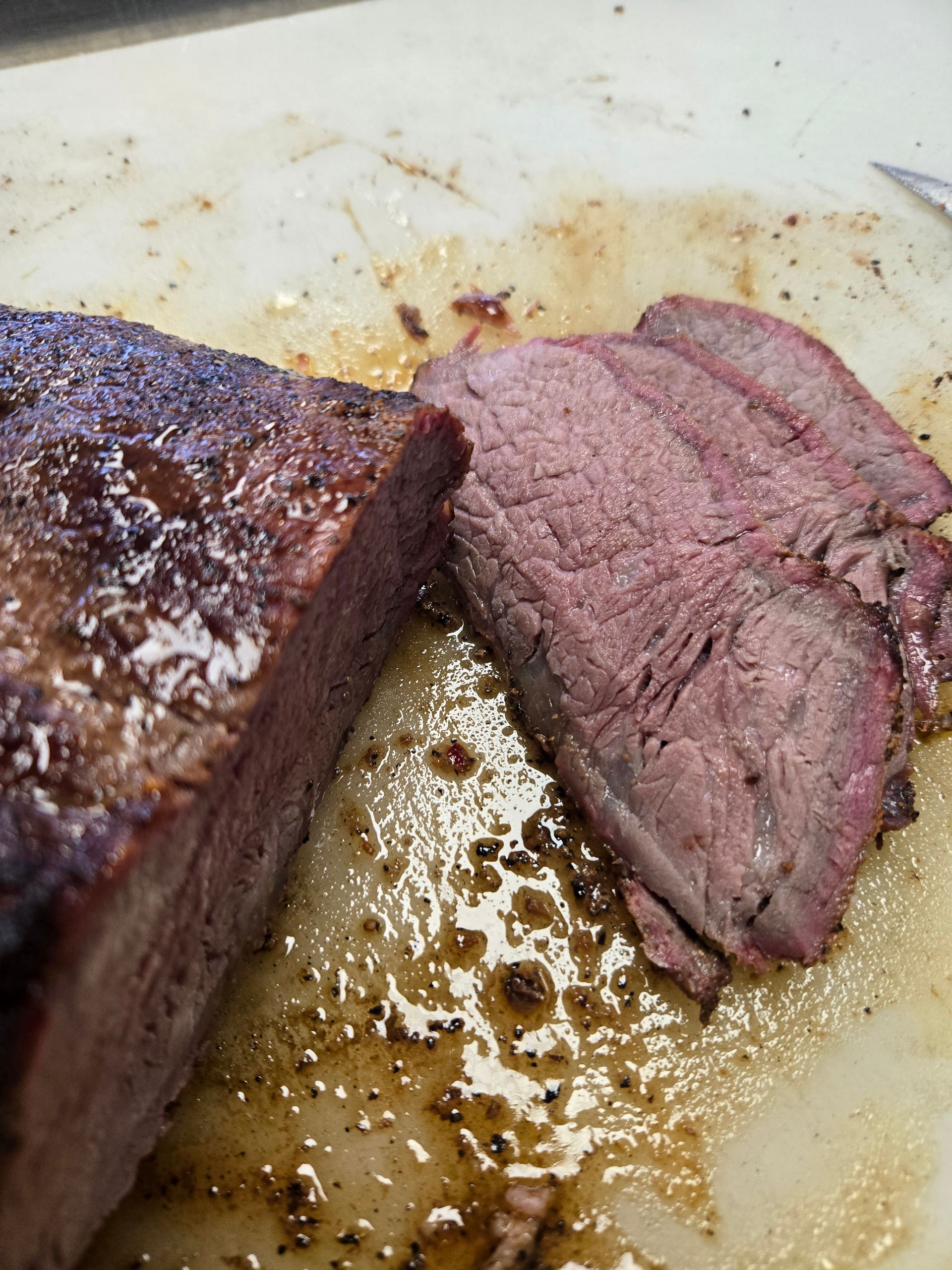 A piece of meat is being sliced on a cutting board.