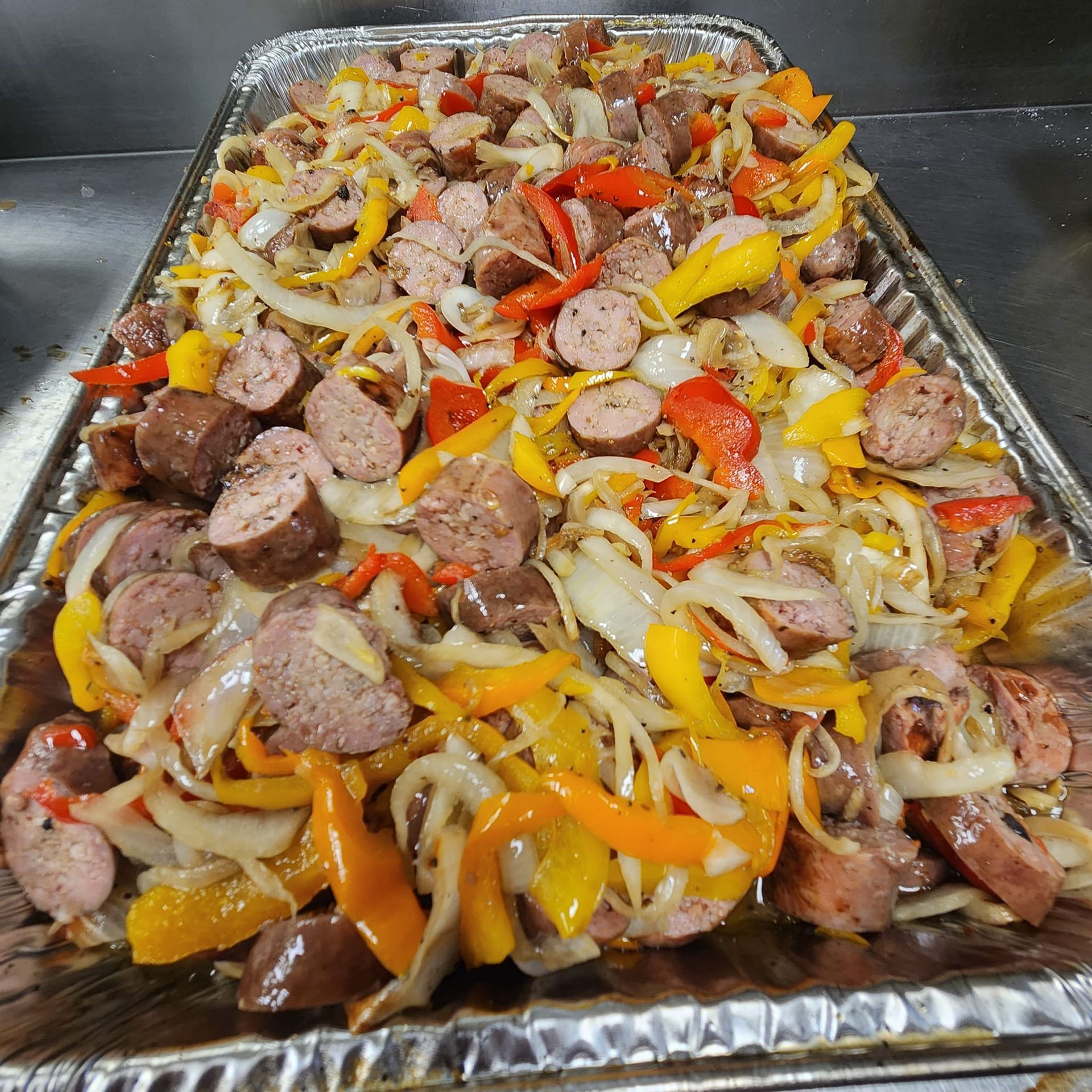 A pan filled with sausage , peppers , onions and cheese.